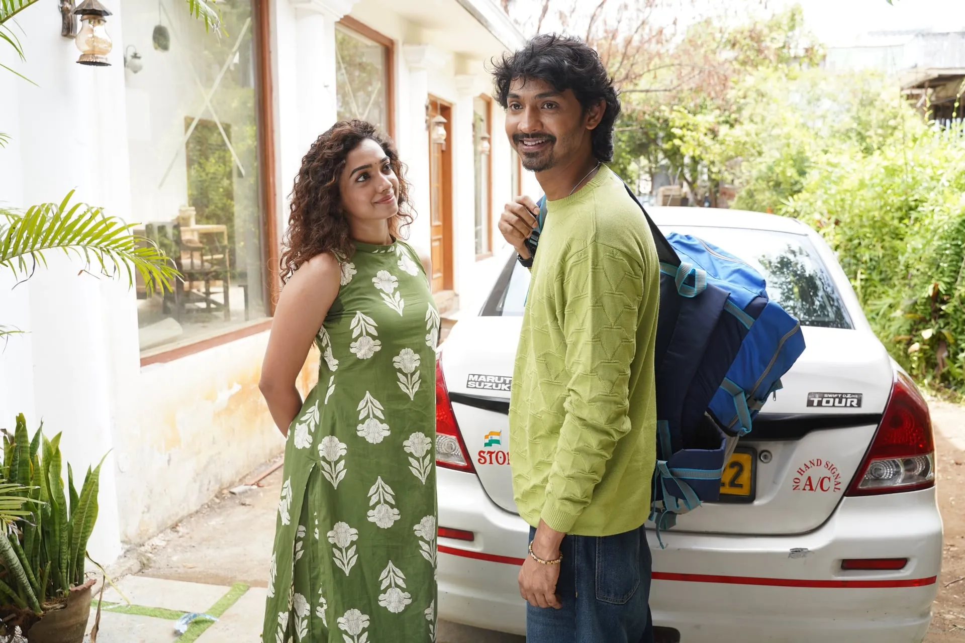 Saanve Meghana and Elan share a smile outside a house, a taxi loaded with his luggage behind them, in Pyaar Prema Kalyanam