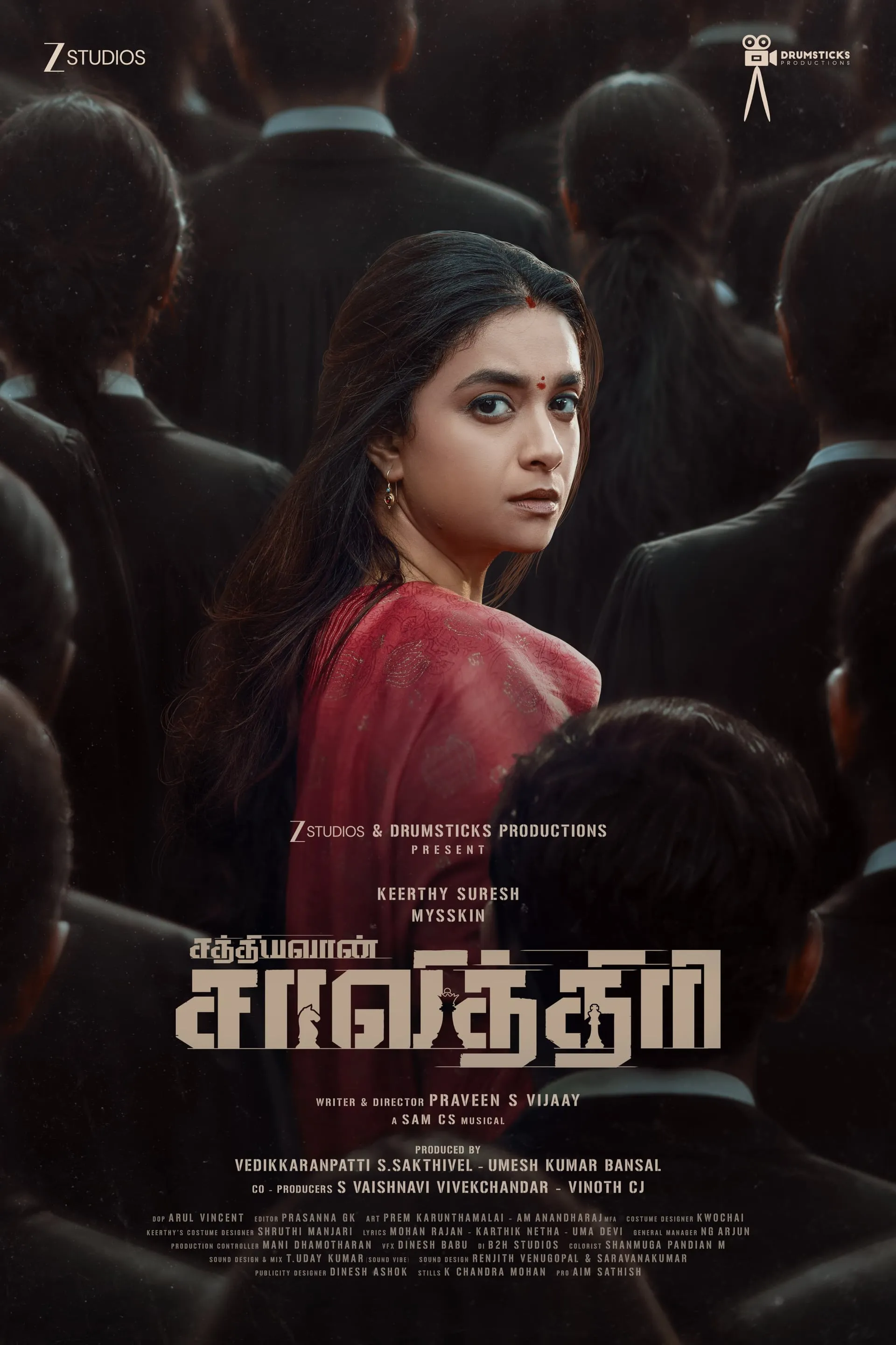 Keerthy Suresh in a red sari turning back amidst a crowd of male lawyers in black robes, second-look poster for Sathyavan Savithri