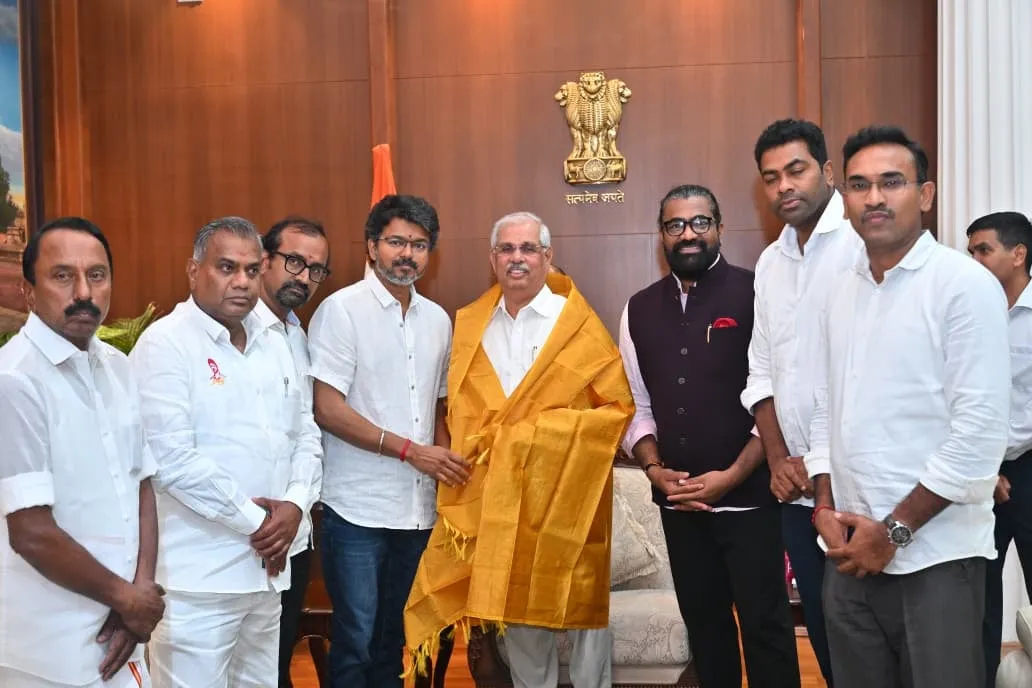 Vijay shaking hands with Tamil Nadu Governor Rajendra Vishwanath Arlekar at Lok Bhavan, the Governor draped in a yellow shawl, with the TVK delegation around them