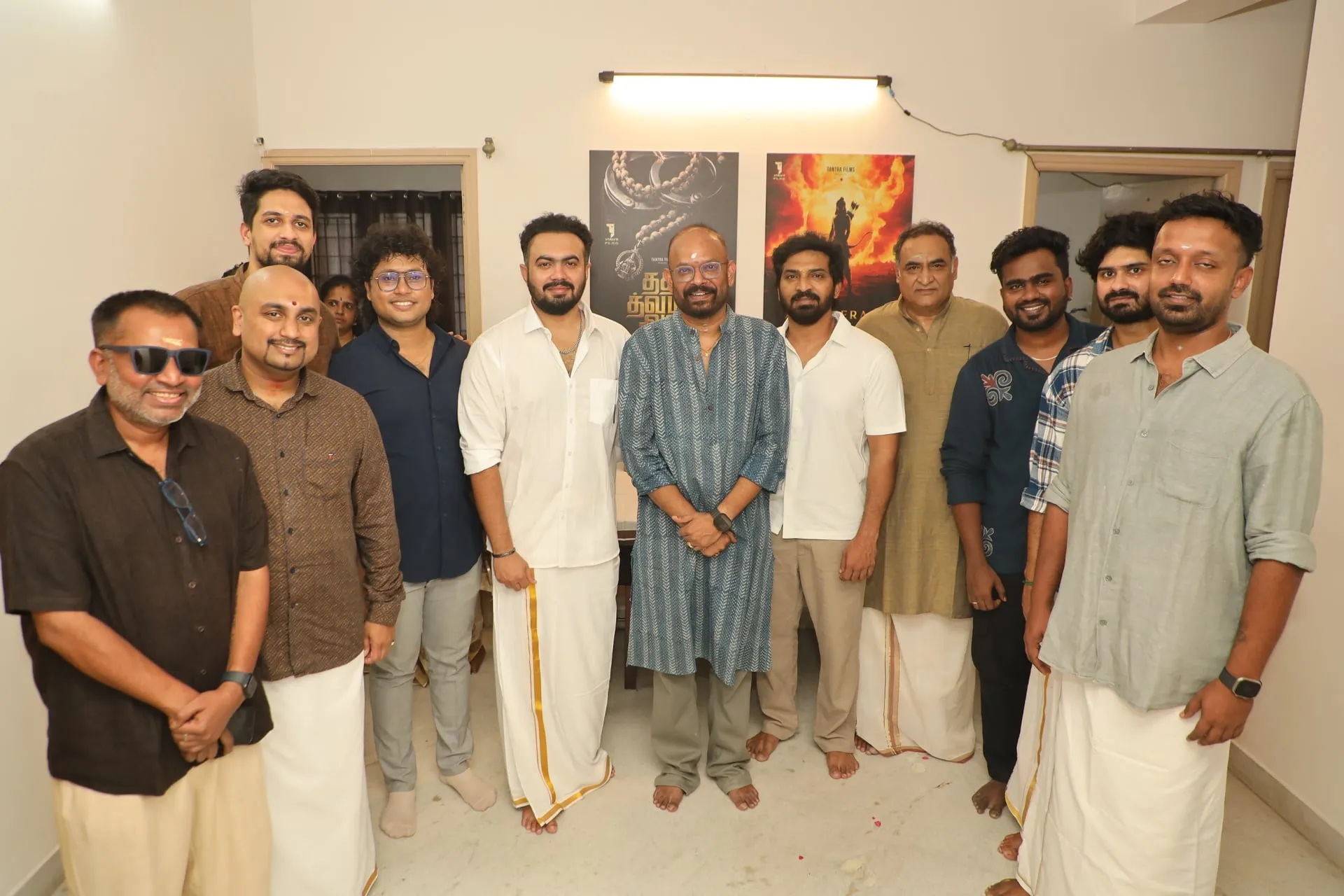 The cast and crew of Tat Twam Assi at the film's launch, with the Tat Twam Assi and Arya Kerala Varman posters behind them