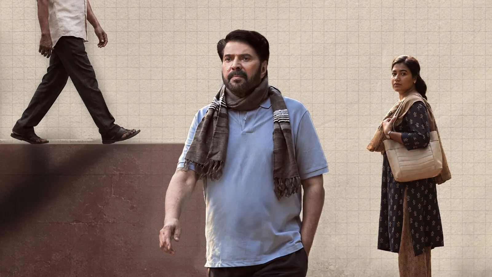 Mammootty in a blue shirt and checked scarf walks past a tiled wall as Grace Antony looks on in the Padayaatra release date poster