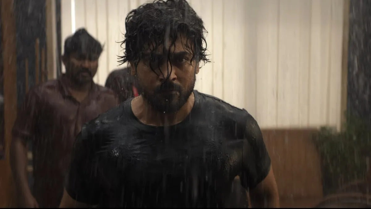 Suriya, soaked and unshaven in a black T-shirt, walks through a corridor in a still from Scene