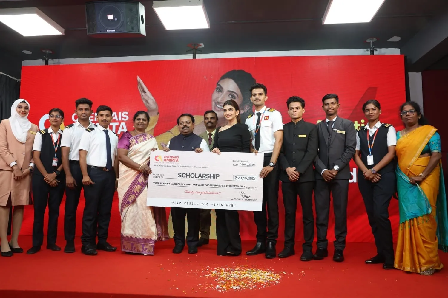 Sreeleela on stage at Chennais Amirta Aviation College holding a giant scholarship cheque worth Rs 28,45,250 with students lined up beside her