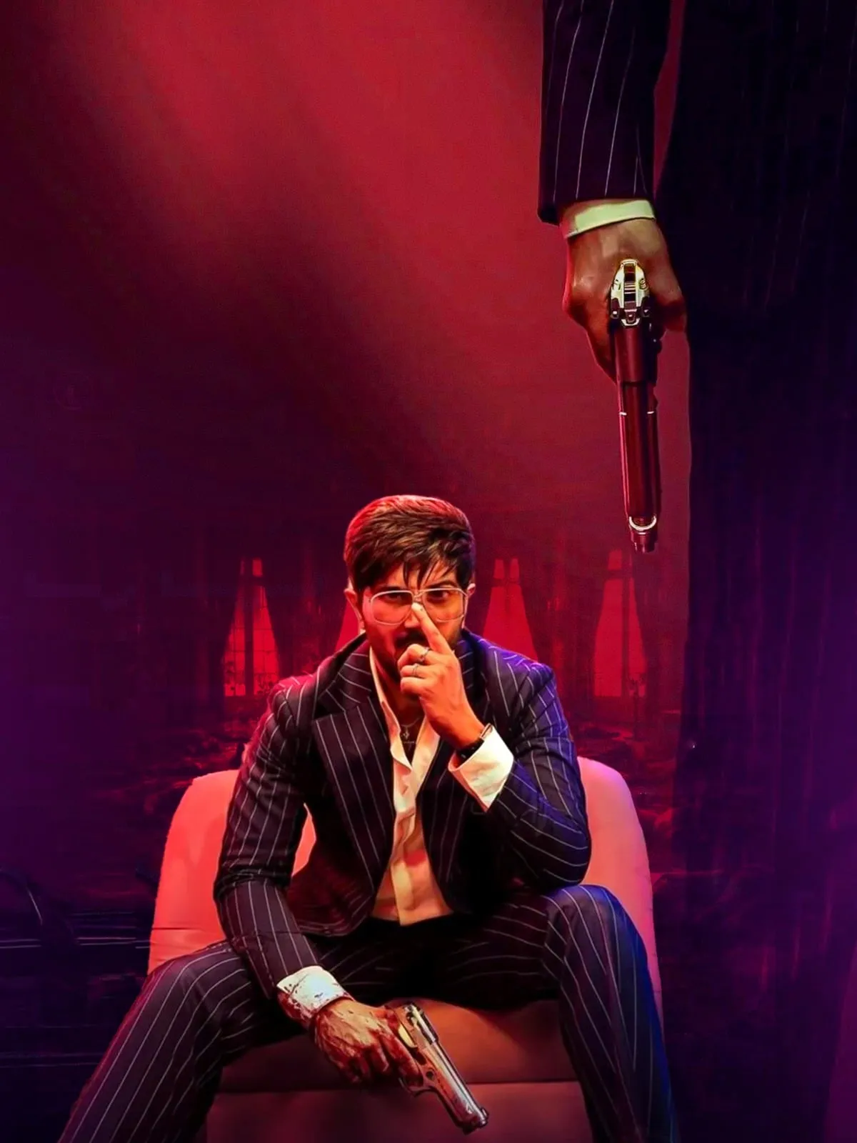 Dulquer Salmaan in a pinstriped suit with a revolver in hand on the I'm Game poster