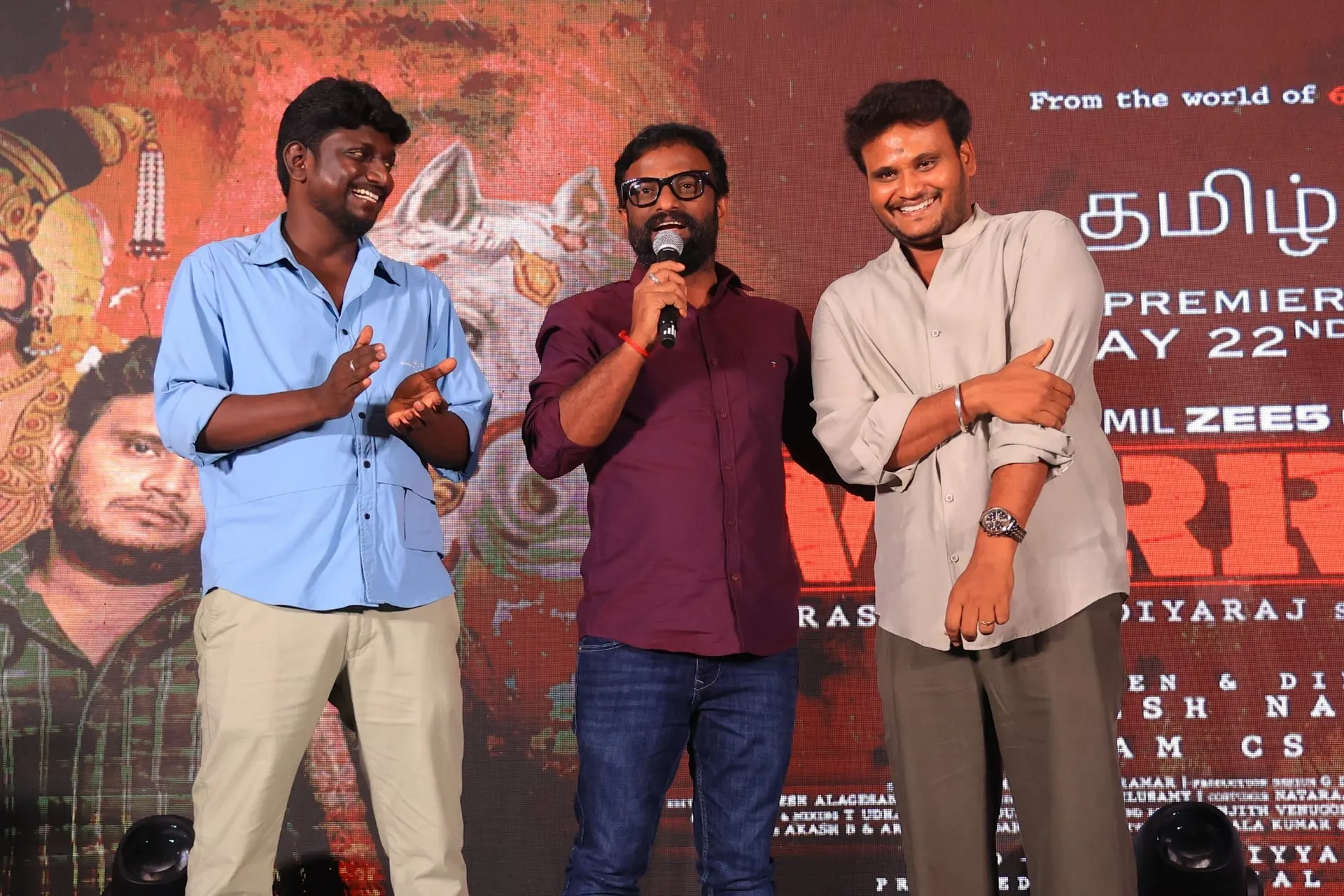 Director Pandiraj at the centre of the Warrant trailer launch stage with director Vignesh Natarajan on the left and lead actor Prasanth Pandiyaraj on the right, against a Tamil ZEE5 May 22 backdrop