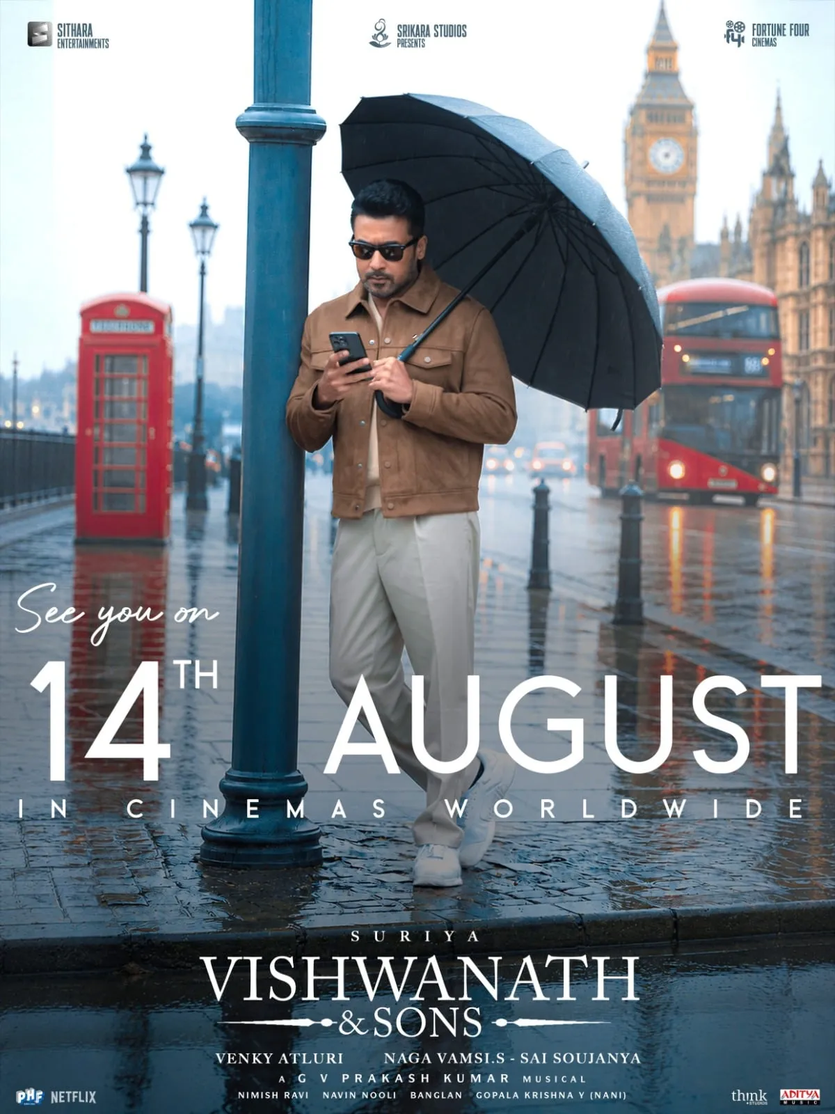 Vishwanath & Sons release-date poster showing Suriya under an umbrella on a rainy London street, set for August 14 worldwide