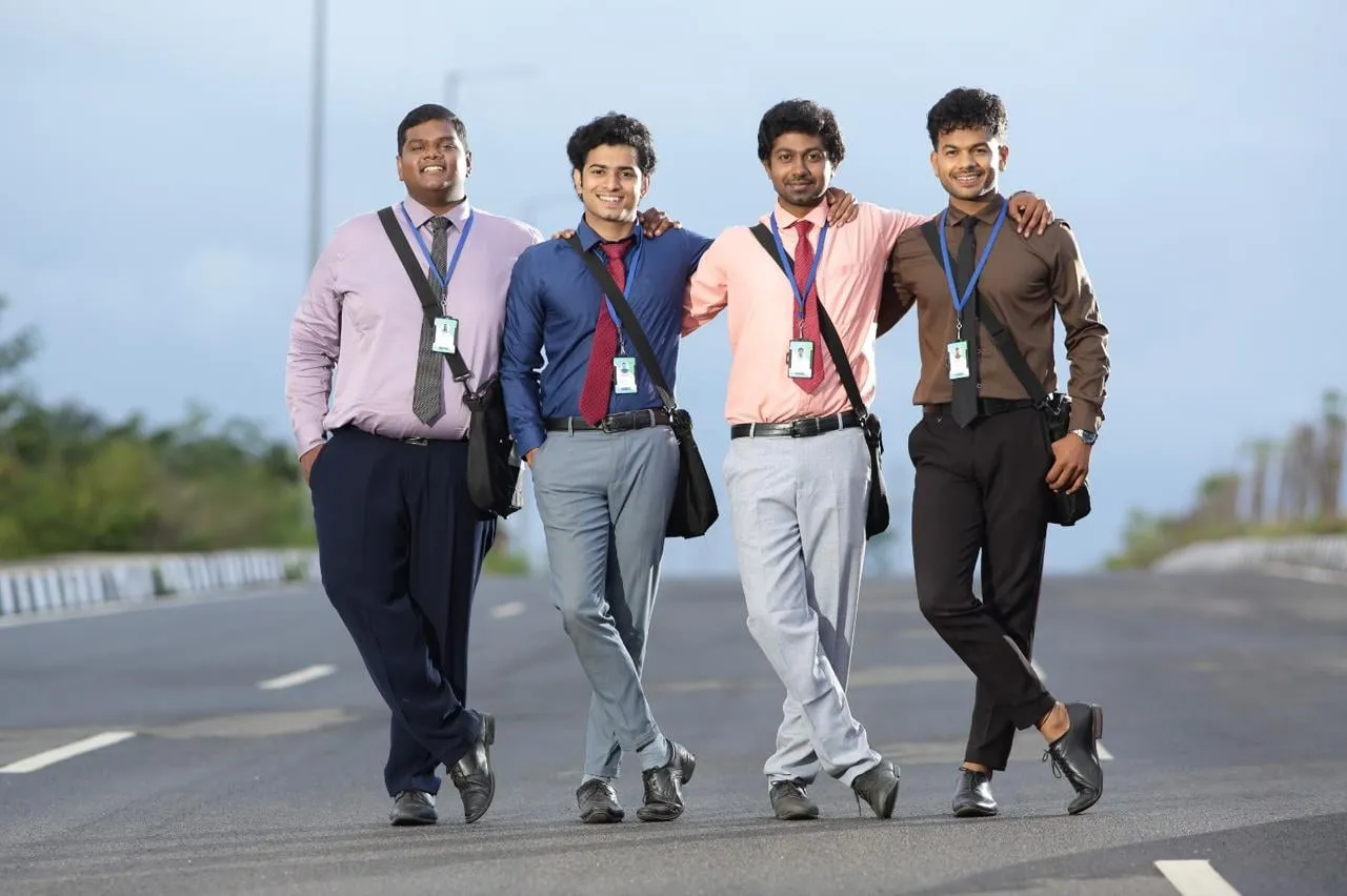 Four friends wearing office shirts, ties and identity cards walk together along a road in Cold Call