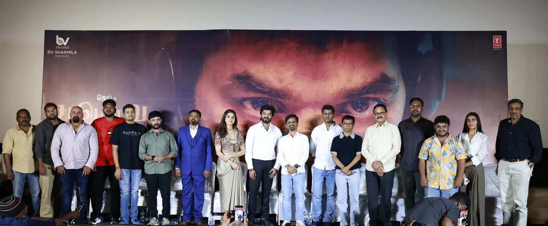Cast and crew of Sattendru Maarudhu Vaanilai on stage at the film's pre-release event in T Nagar, lined up in front of a giant Jai close-up poster