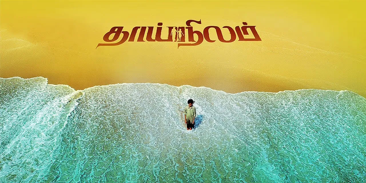 Thaainilam poster: an aerial shot of a young girl standing alone in the surf on a yellow beach, the Tamil title written in the sand above her