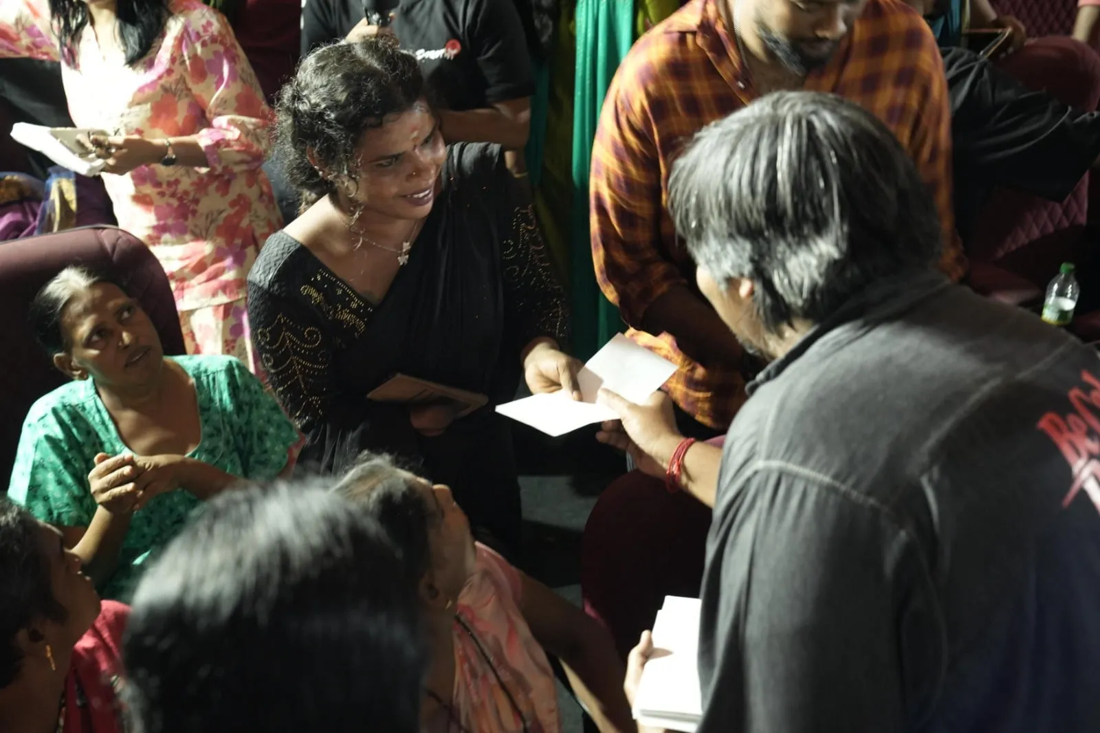 Karthik Subbaraj hands a cheque to a member of the transgender community seated in a theatre