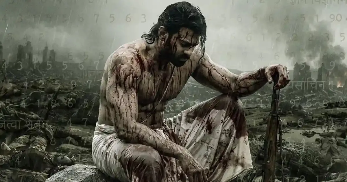 A bloodied, shirtless Prabhas sits with a rifle on a smoking battlefield in the Fauzi poster