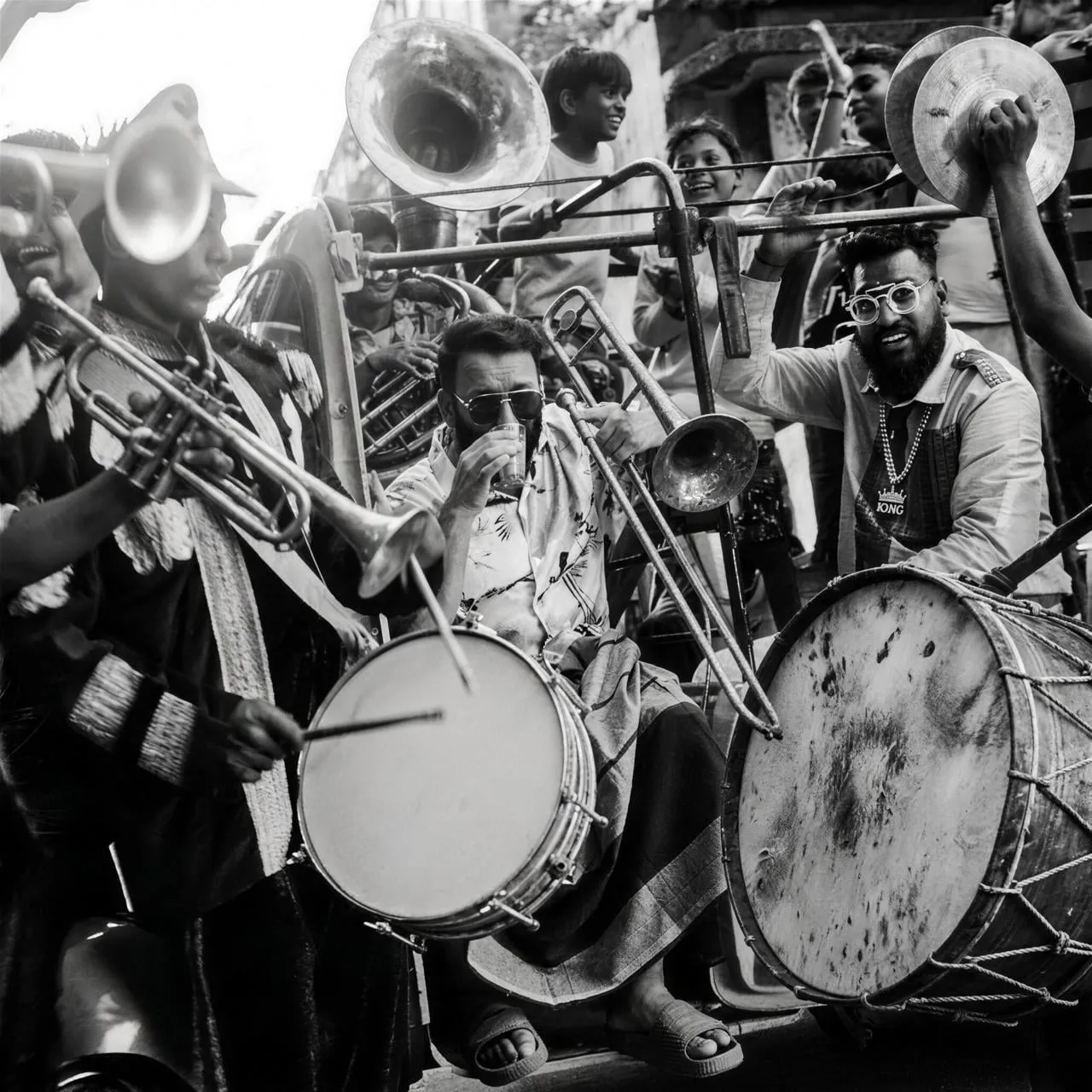 A street brass band performs surrounded by cheering children in the Mannaru music video