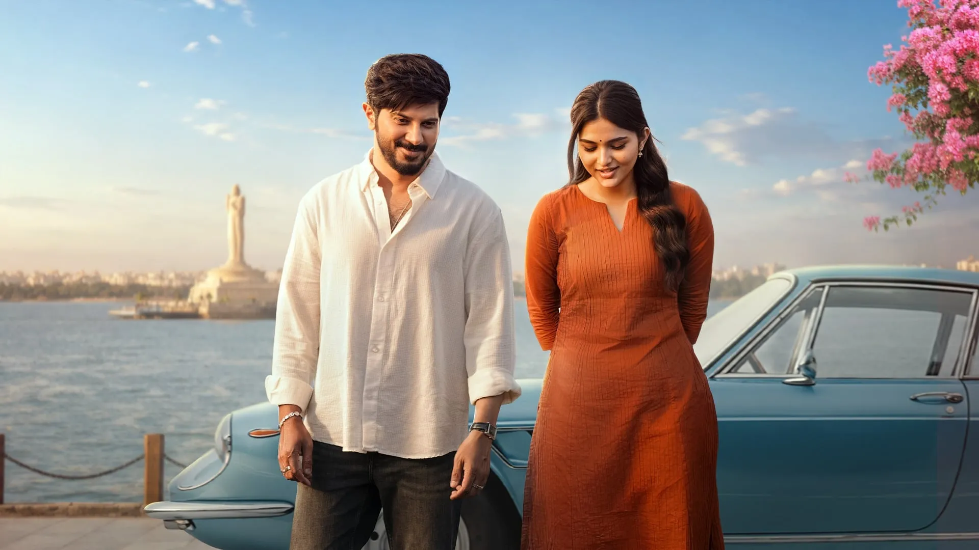 Dulquer Salmaan and Kayadu Lohar leaning on a vintage blue car by Hyderabad's Hussain Sagar lake in I'm Game, the Buddha statue behind them