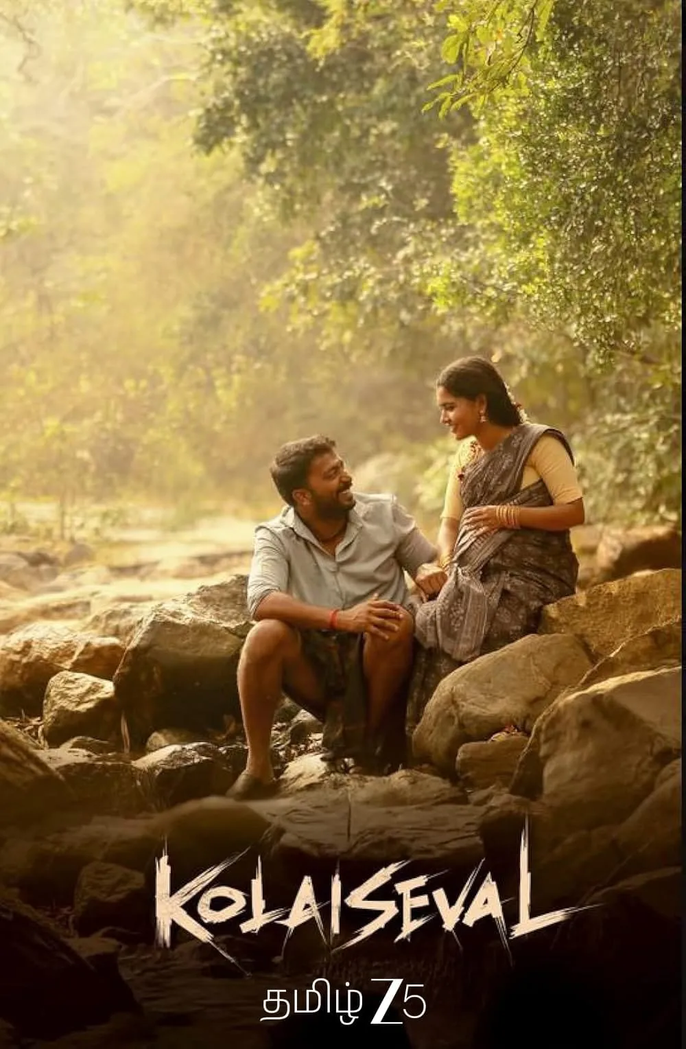 Kolaiseval key art with Kalaiyarasan and Deepa Balu seated on river rocks in a misty forest, the title in jagged white letters at the foot of the frame