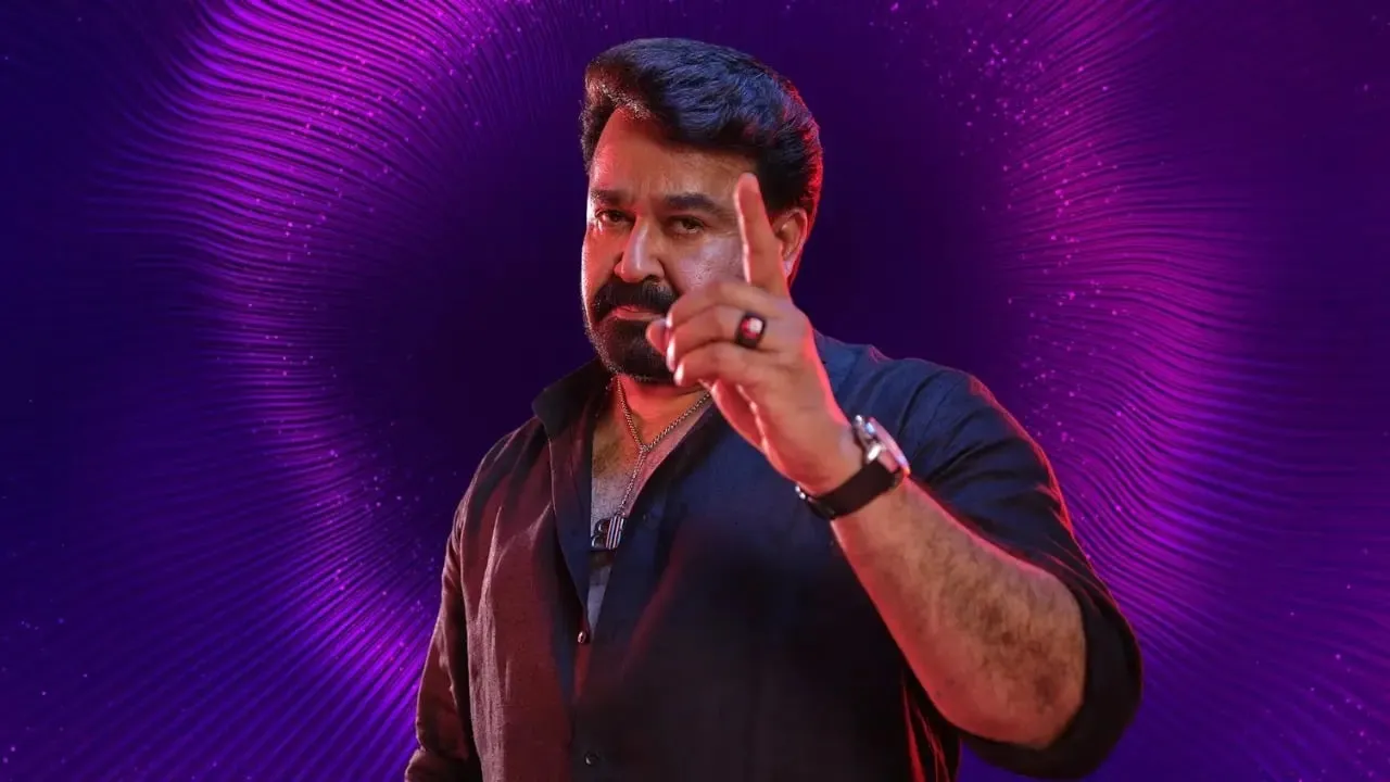Mohanlal in a black kurta with a raised index finger, lit by warm key light against a purple textured backdrop, in the campaign visual for the Mohanlal - The Complete Actor festival on JioHotstar