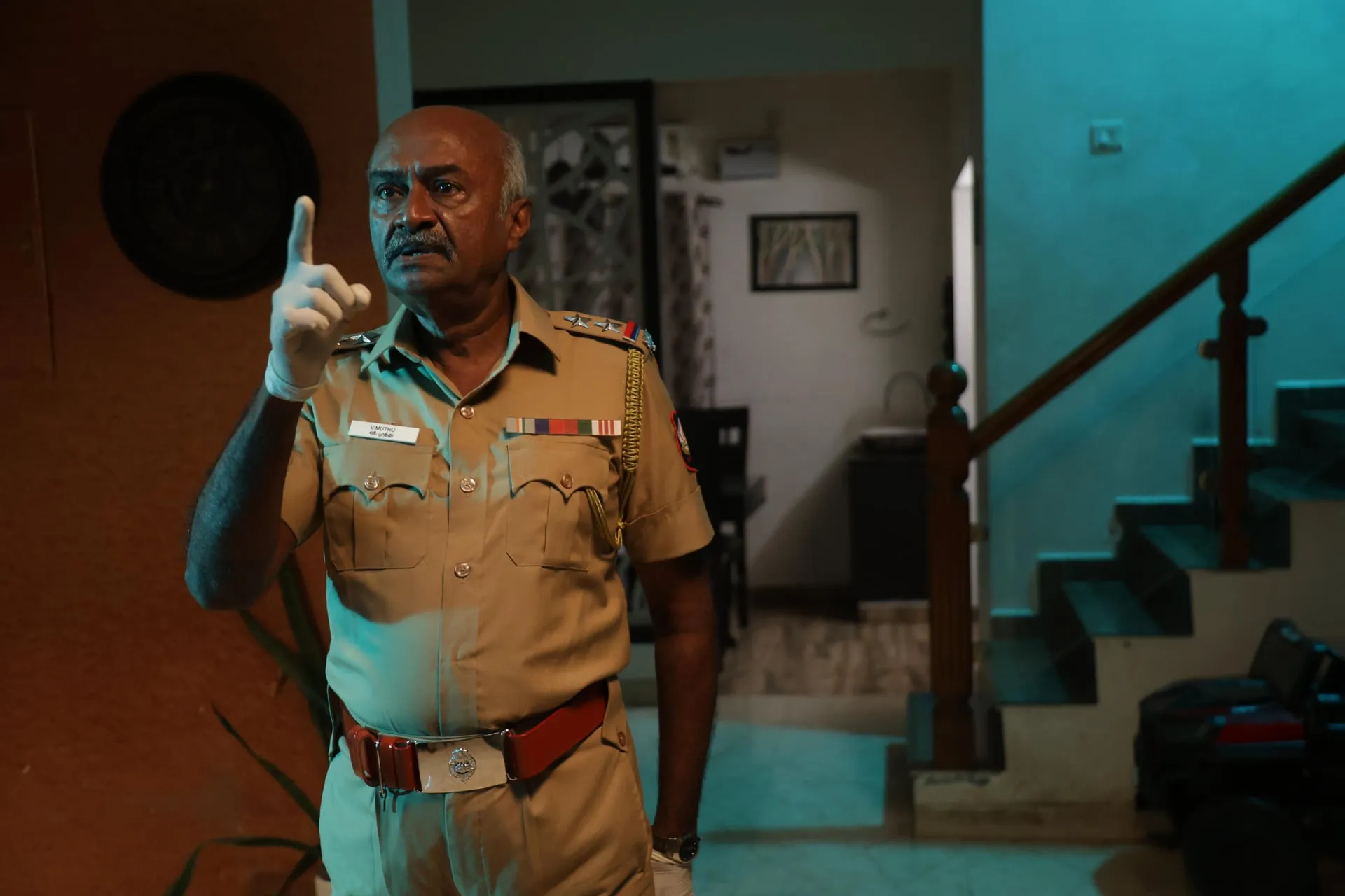 M.S. Bhaskar in police uniform inside a dimly lit house in Vidiyum Kaathiru