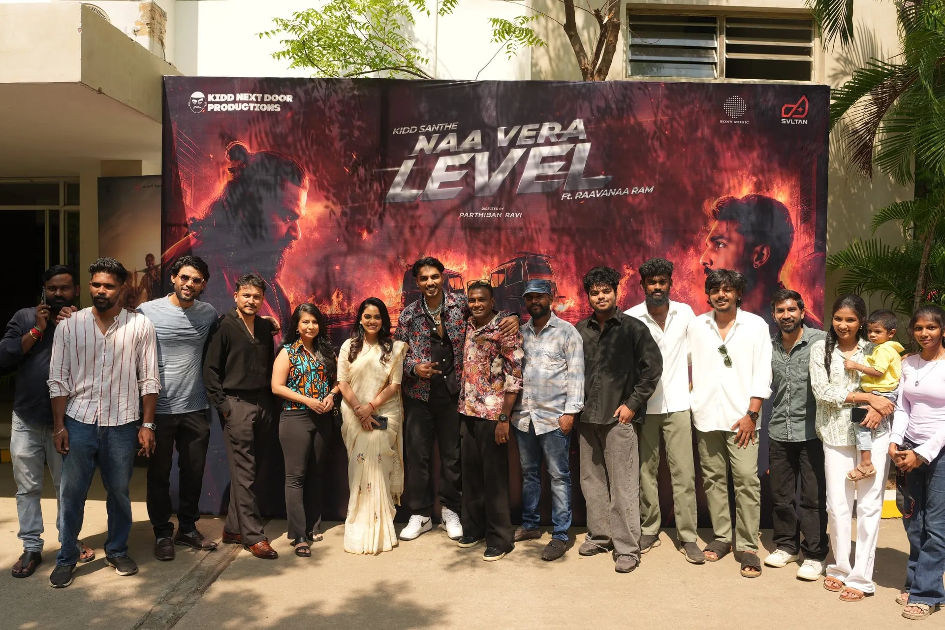 The Kidd Santhe Naa Vera Level team and Sony Music representatives lined up in front of the album poster at the Chennai launch, with Kidd Santhe centre-frame in a printed shirt