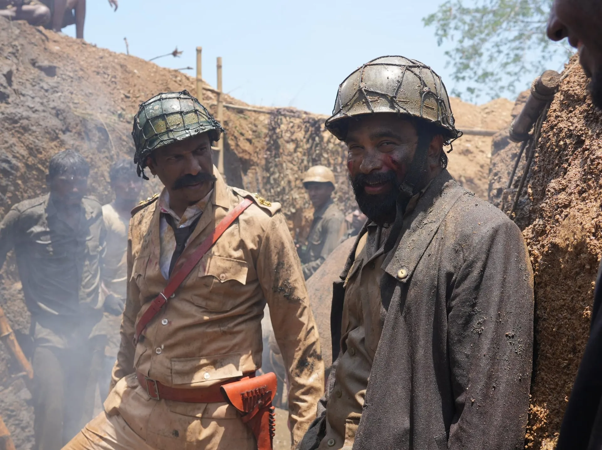 Two soldiers in period helmets and muddy uniforms in a trench on the set of Dharani Rasendran's Sasikumar war drama