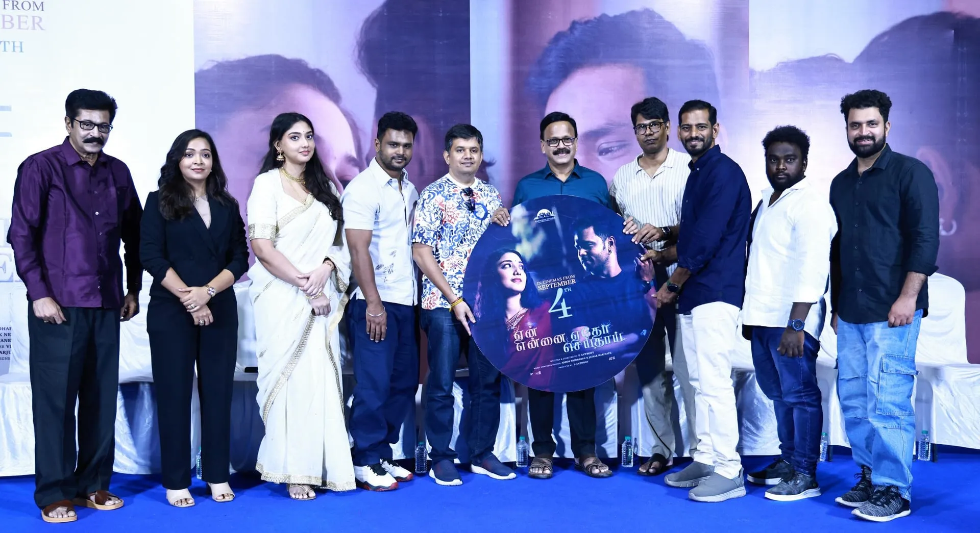 The Yen Ennai Edho Seidhai cast and crew onstage holding the film's circular release poster