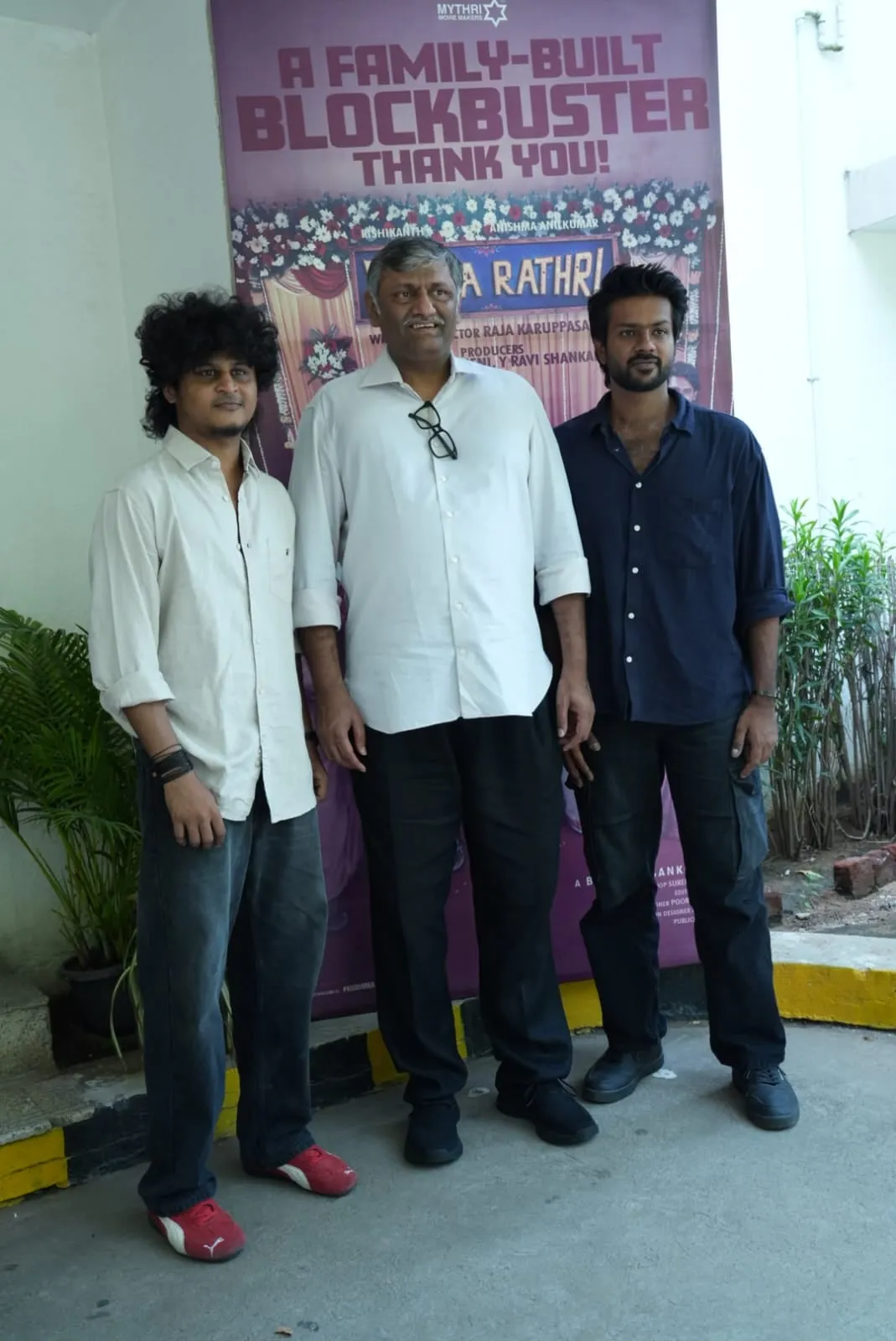 Three attendees pose together beside the Modha Rathri thank-you display
