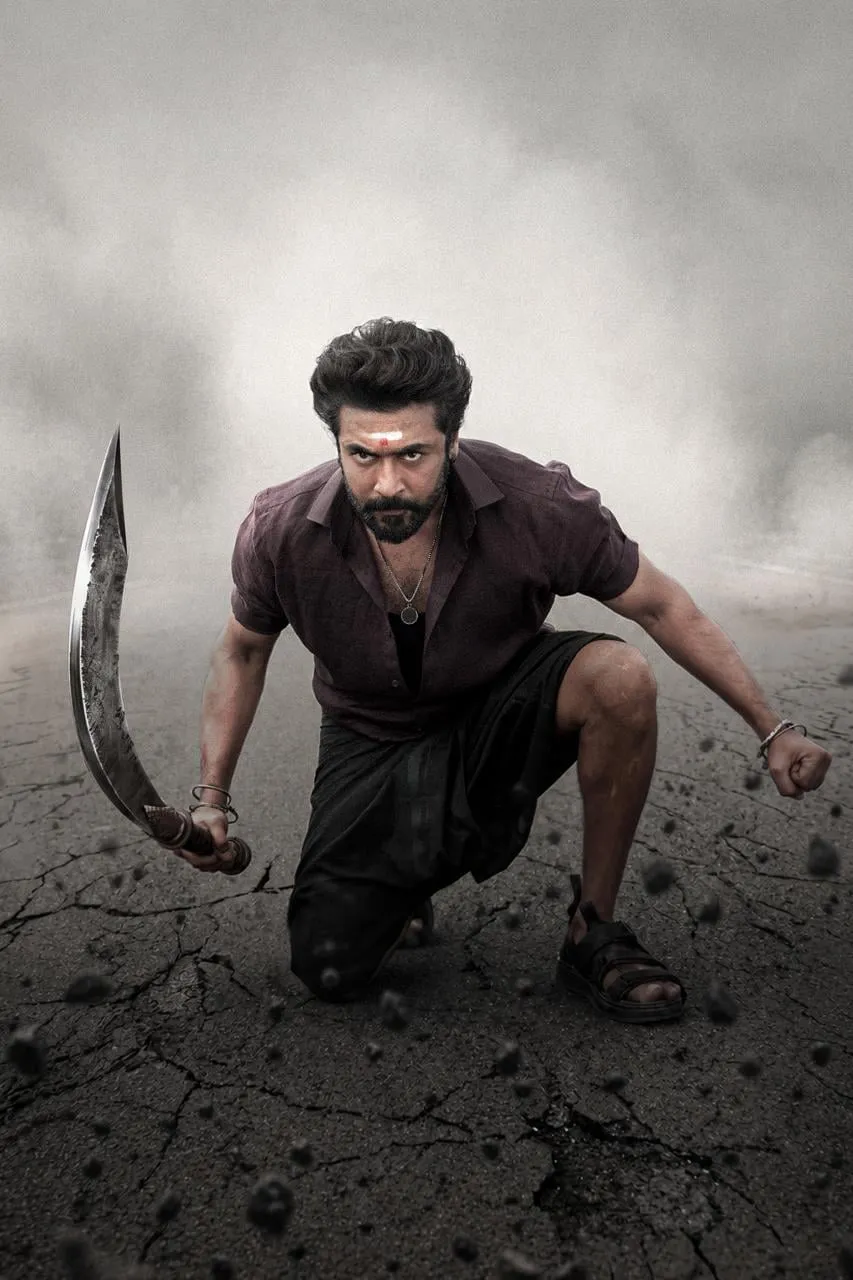 Suriya in Karuppu mode, crouched on a cracked road with a curved aruval, the daylight blown out behind him