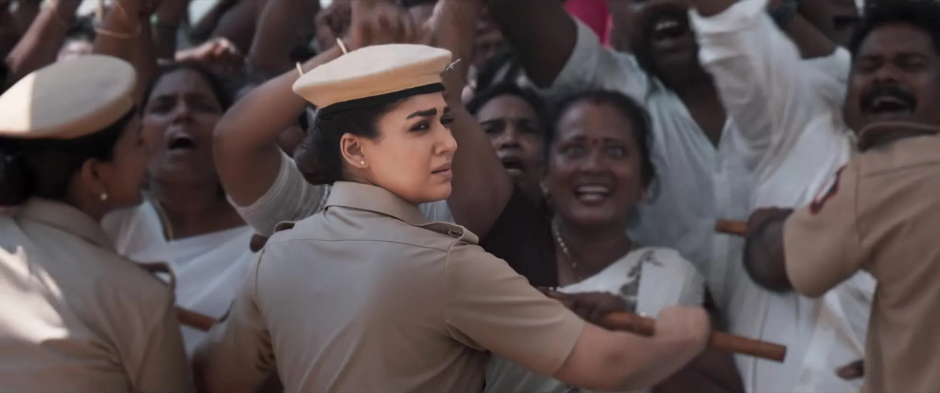 Nayanthara in police uniform pushes through a crowd of devotees