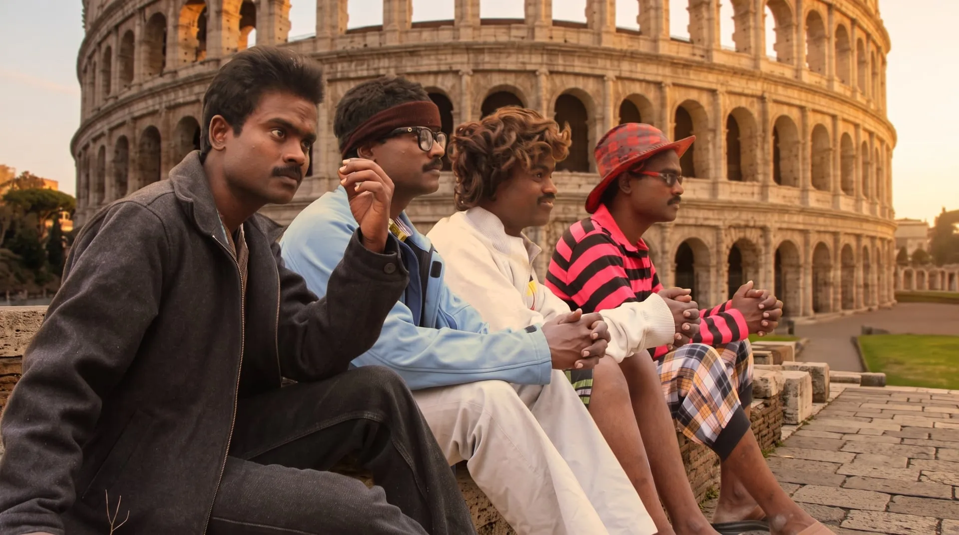 Four versions of Sankagiri Rajkumar in different wigs and costumes seated in a row before the Colosseum
