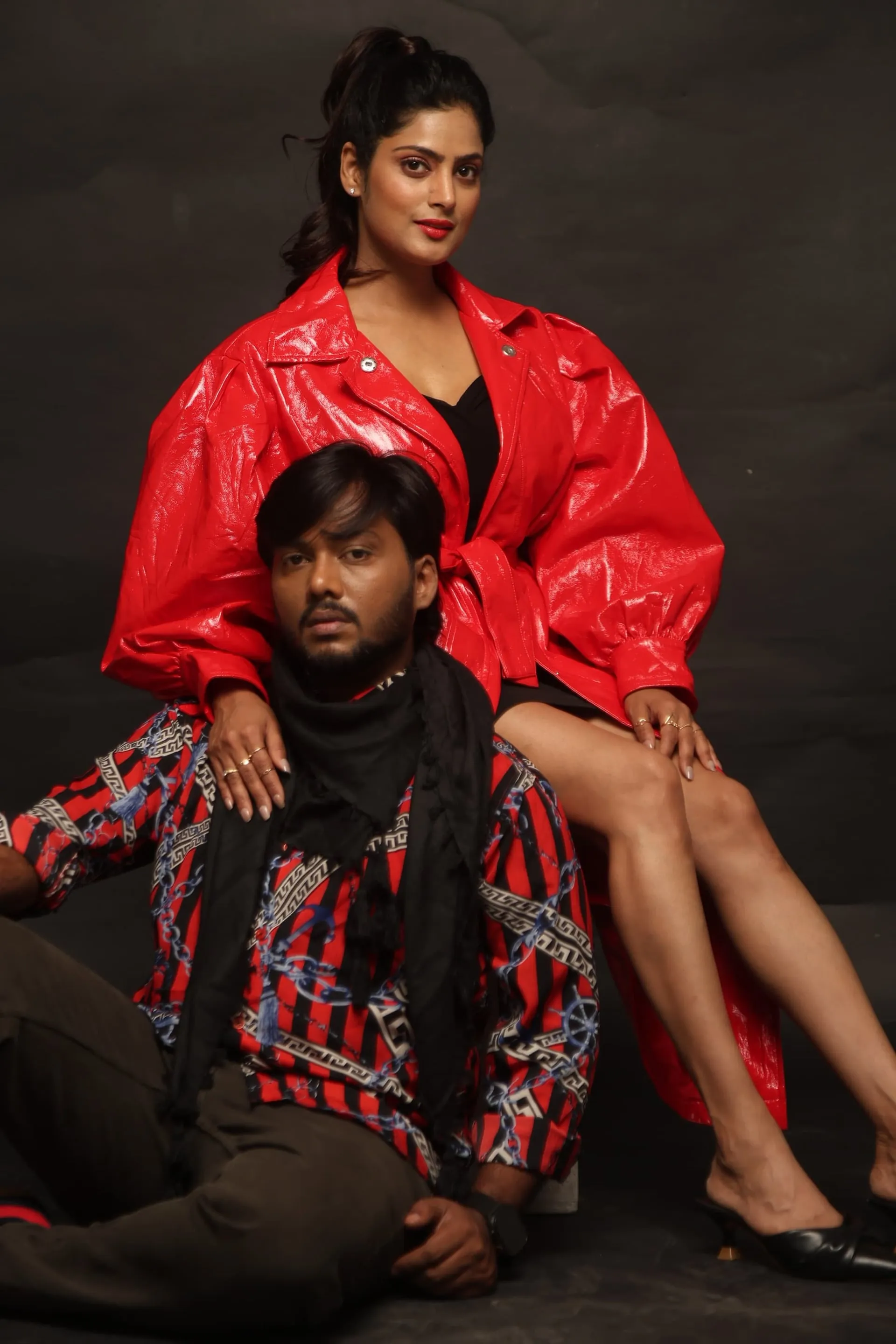 Sherry Agarwal in a red cropped jacket with Nawaz seated below, from a Cycle Gap photoshoot on a black backdrop