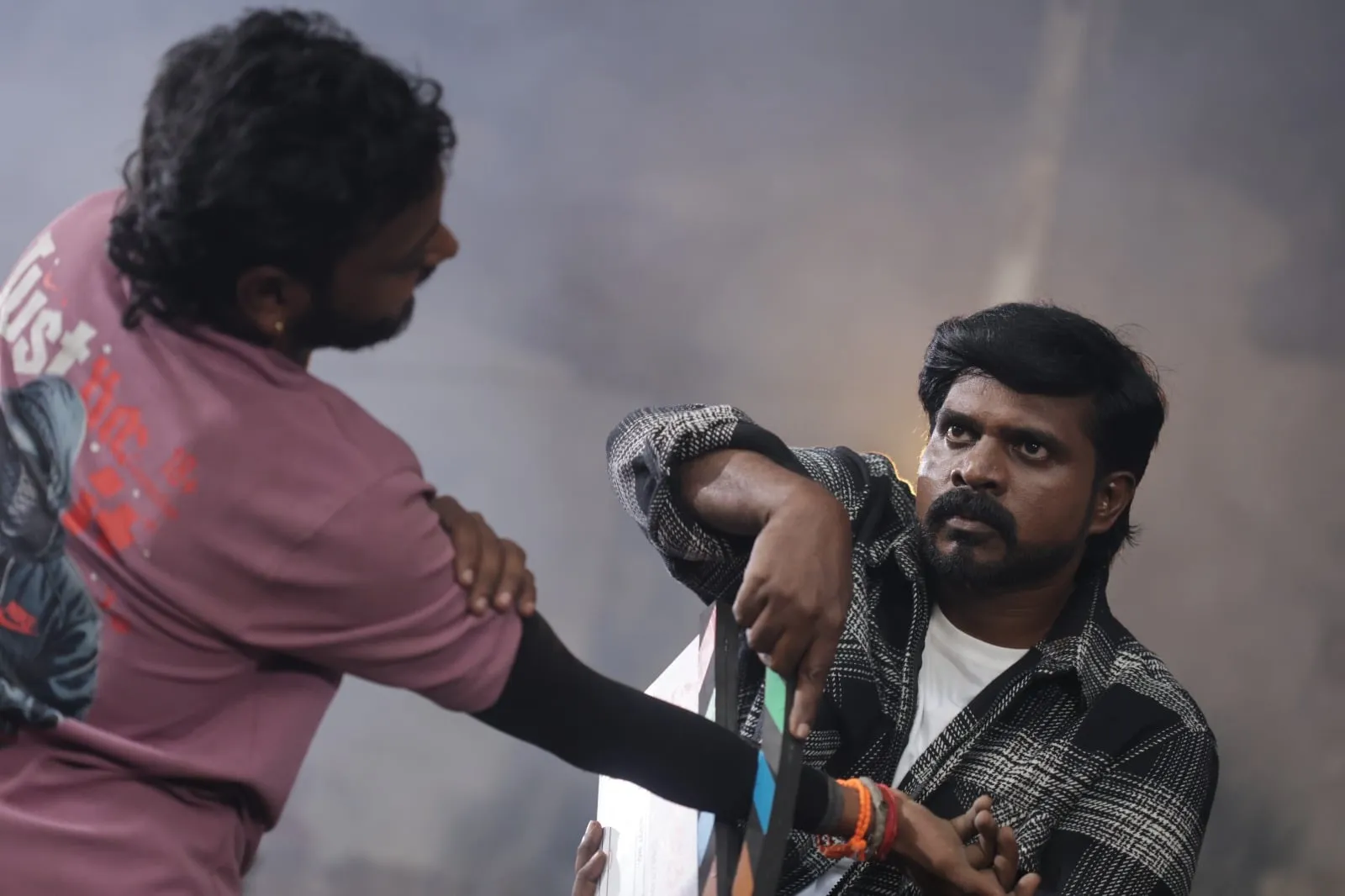 Dhakshan Vijay holds another character by the collar during the filming of an action scene