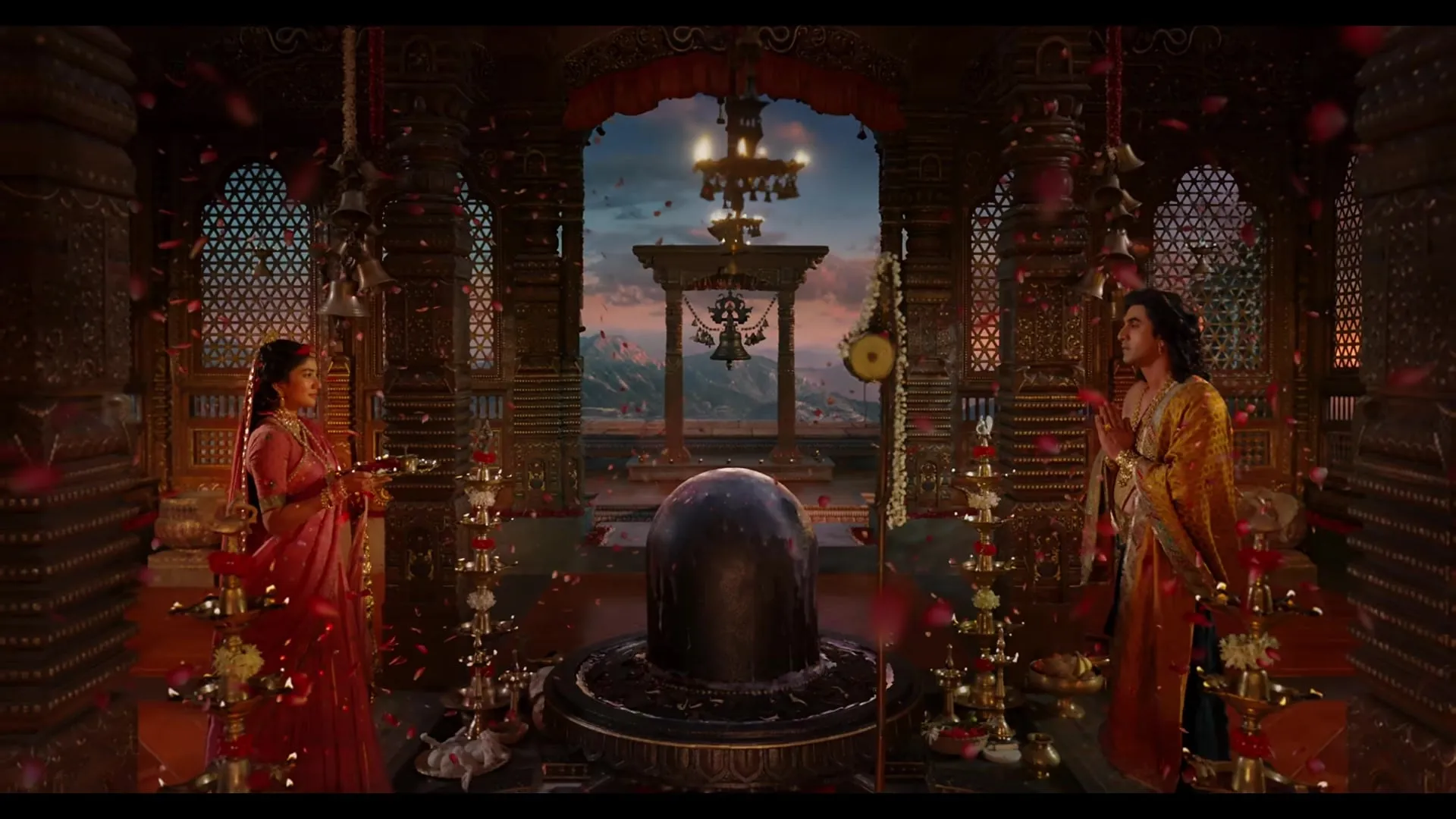 Sita and Rama stand on either side of a Shiva lingam in a palace lit with lamps