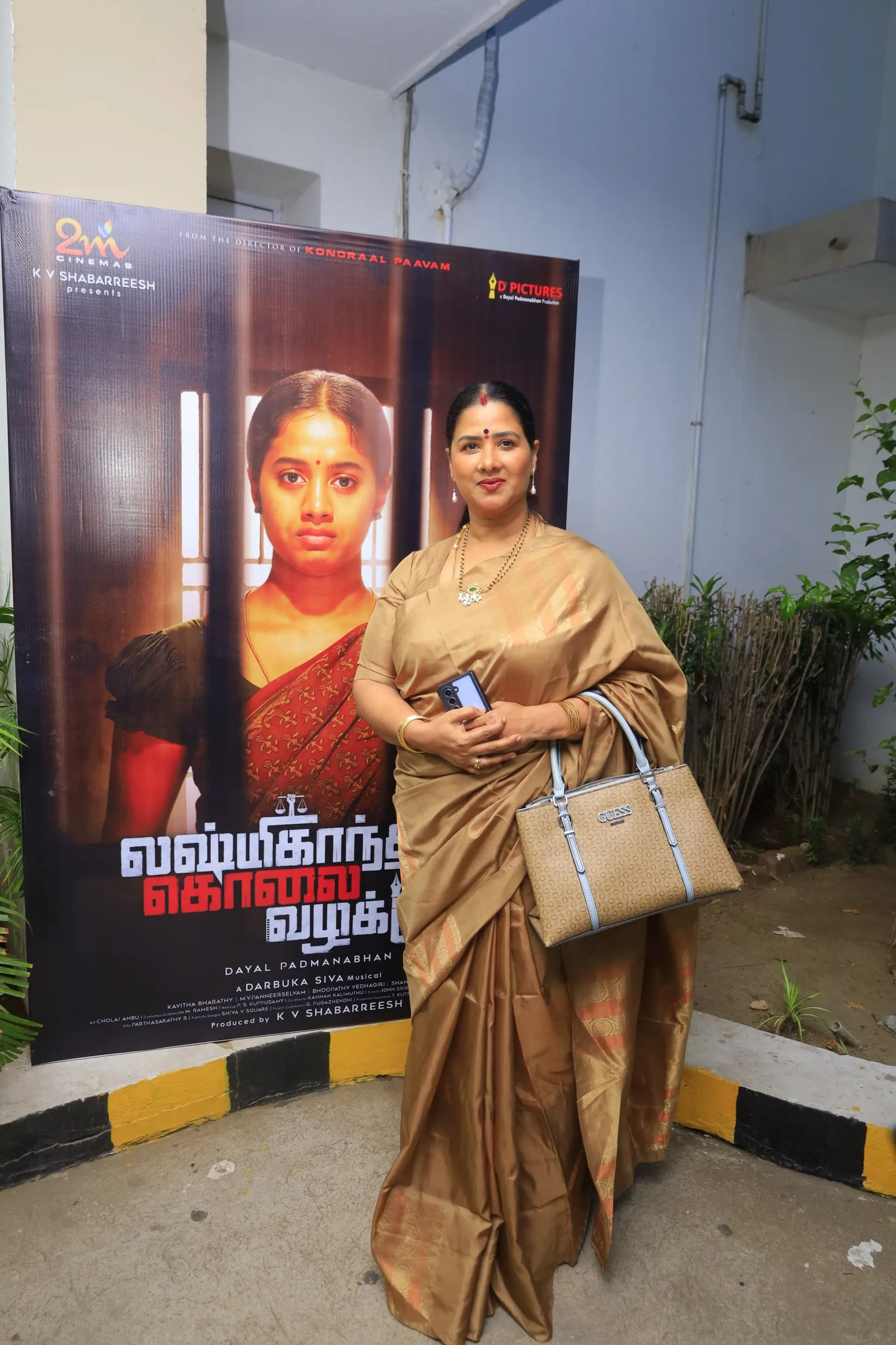 A member of the Lakshmikanthan Kolai Vazhakku cast in front of the film's poster