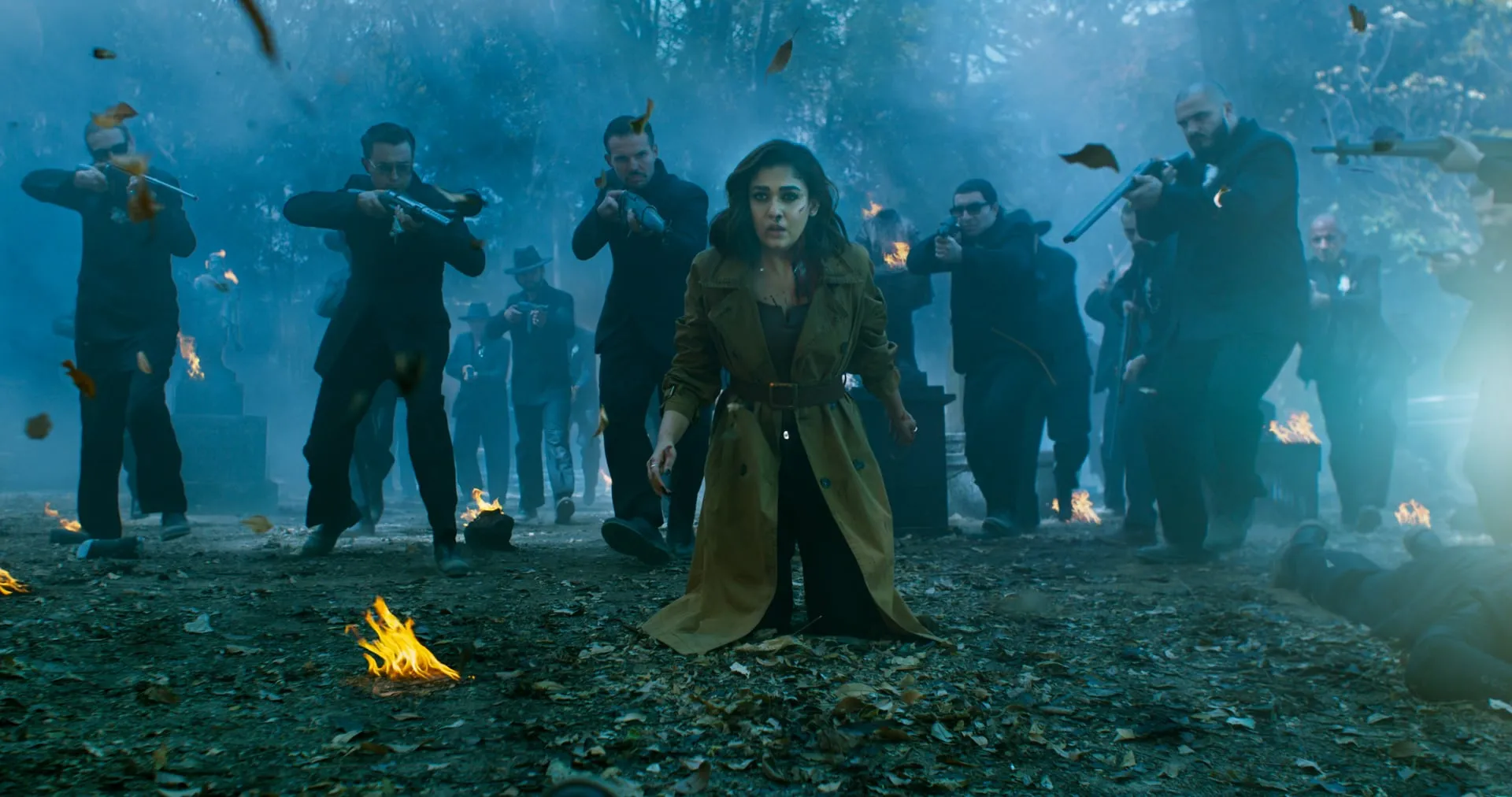 Nayanthara as Ganga in a trench coat, surrounded by armed men in a smoke-filled graveyard