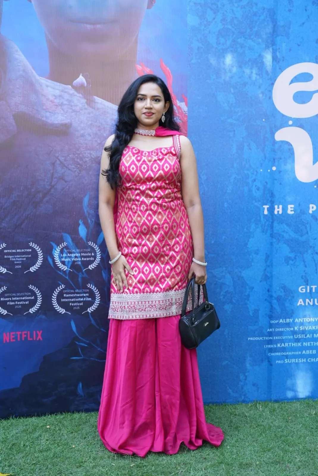 An Enna Vilai cast member poses before the film's trailer-launch backdrop