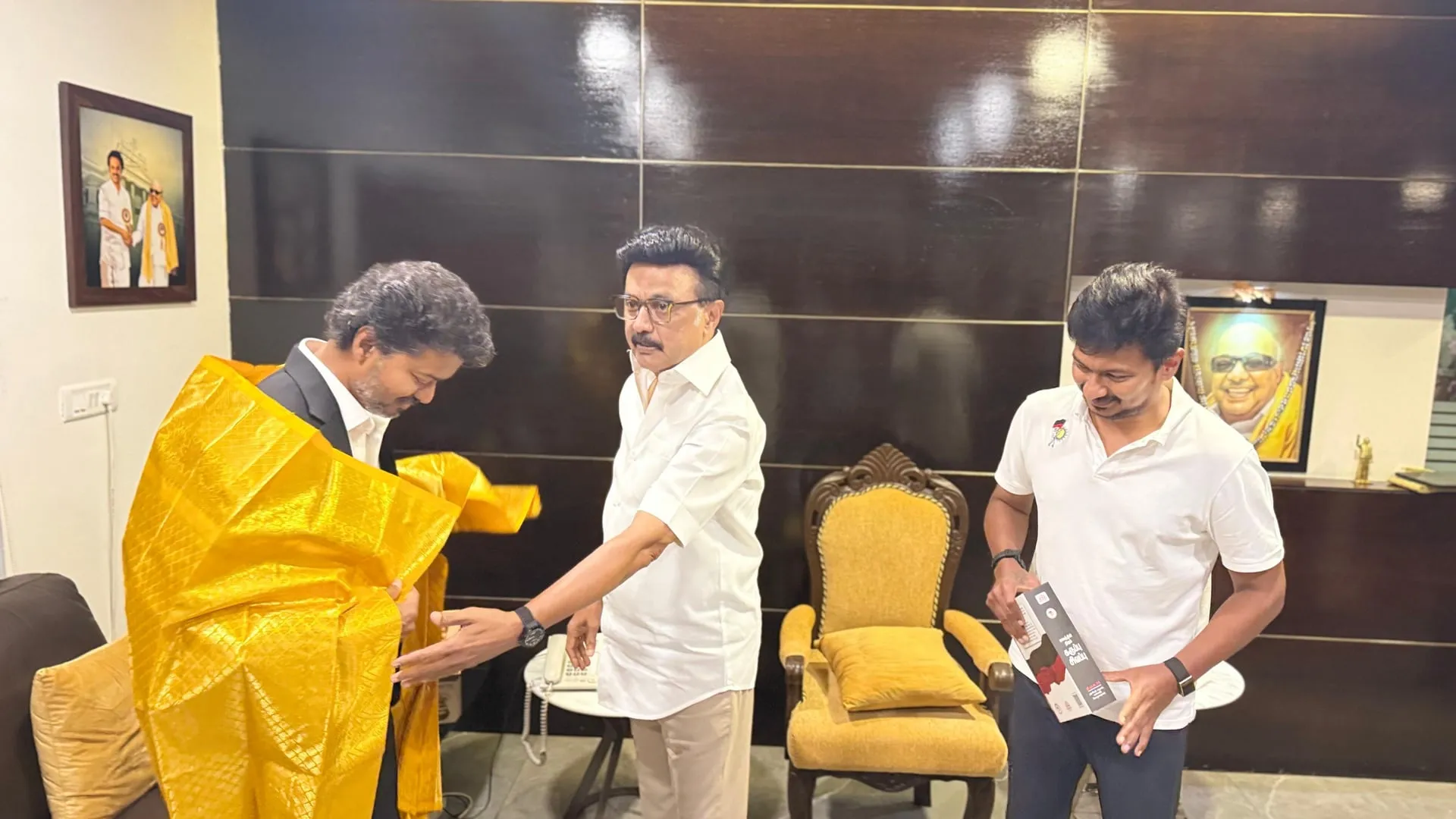 Stalin in the armchair, Vijay and Udhayanidhi on the sofa, with the late Karunanidhi's portrait holding the wall.