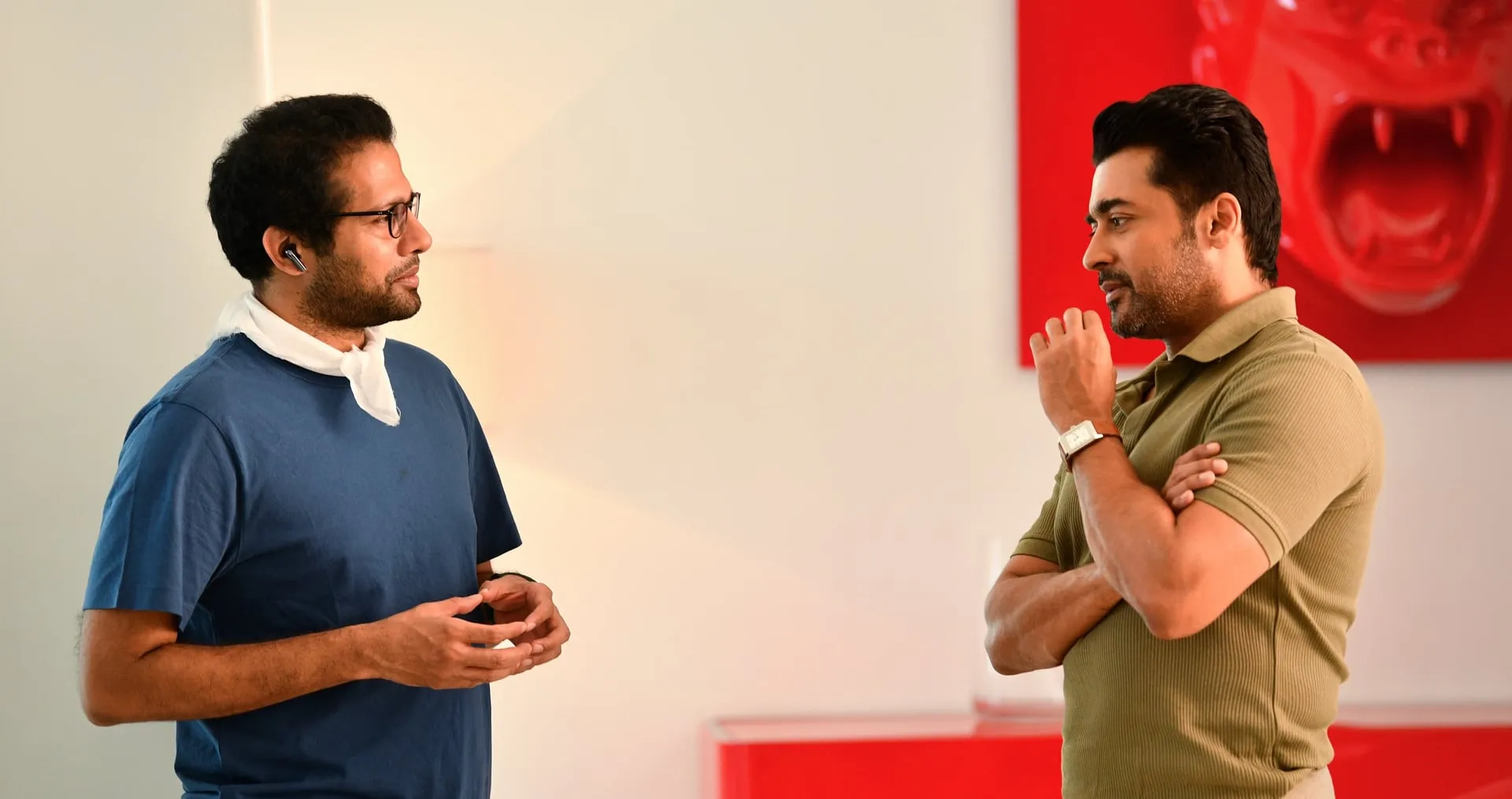 Venky Atluri in discussion with Suriya on an interior set of Vishwanath & Sons with a red gorilla sculpture behind them