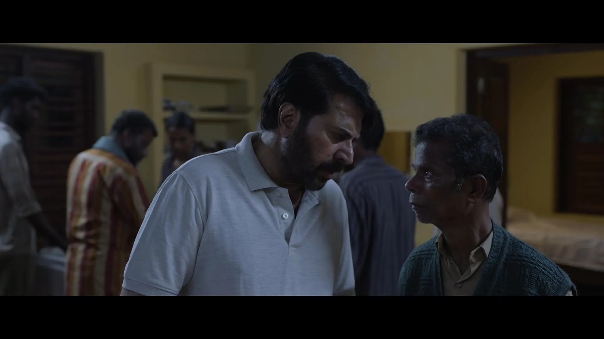 Mammootty, in a grey polo shirt, stands among men in a dim room in the Padayaatra trailer
