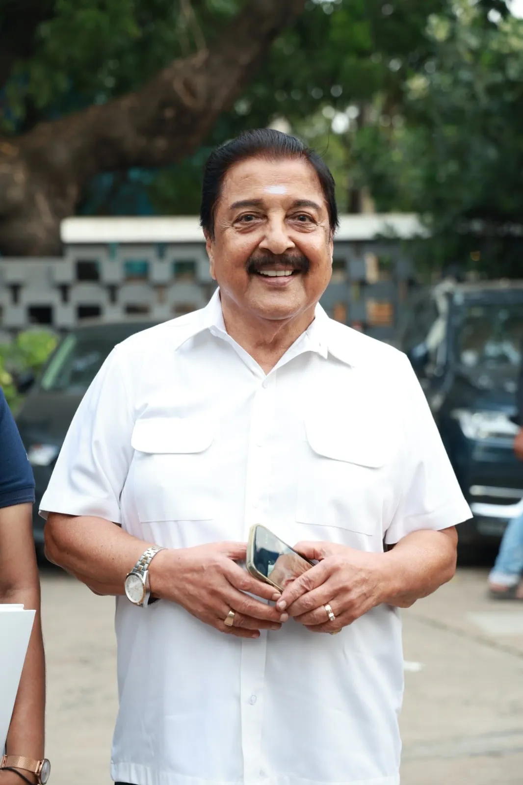 A guest in white smiles outside the event venue