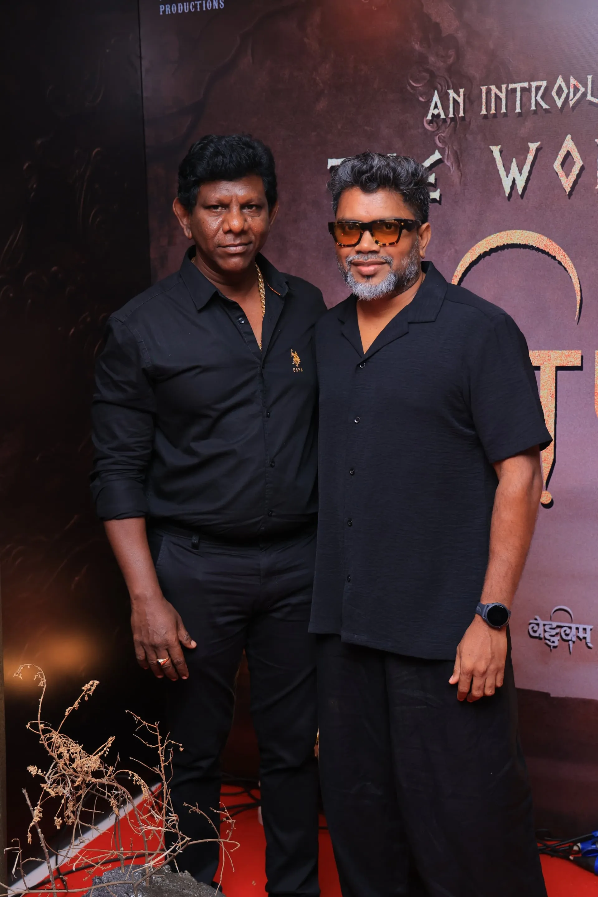 Two Vettuvam team members pose before the event backdrop