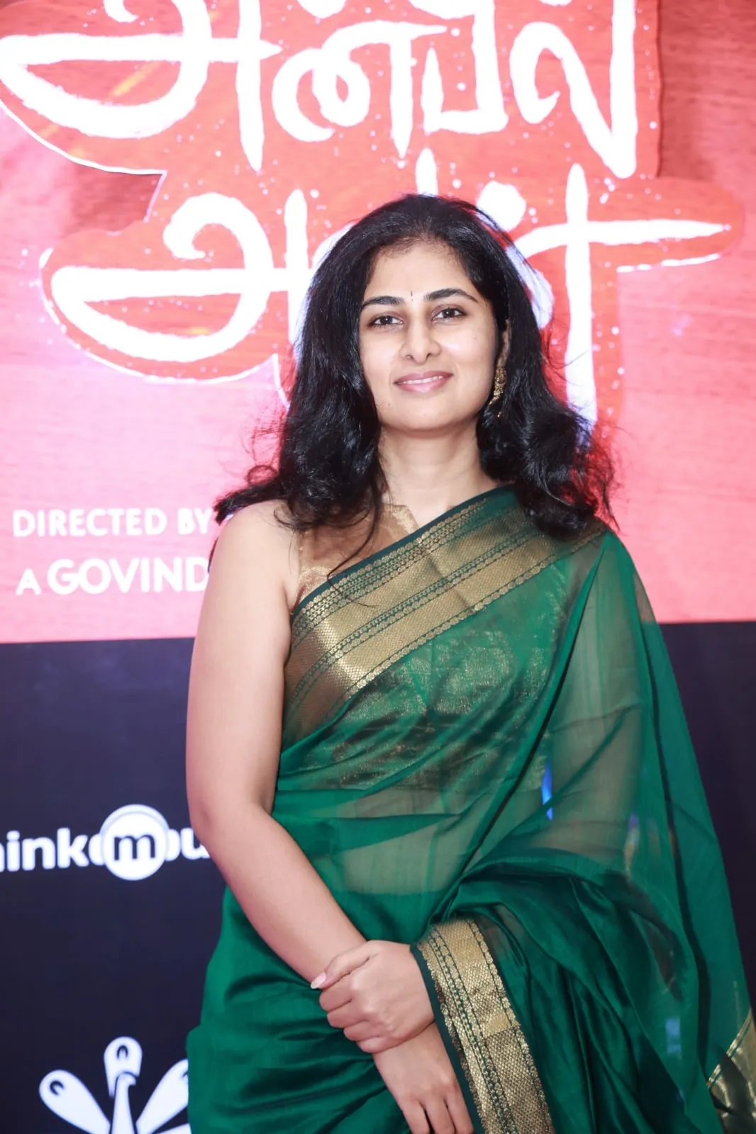 Portrait in a green sari in front of the Anbil Avan event display