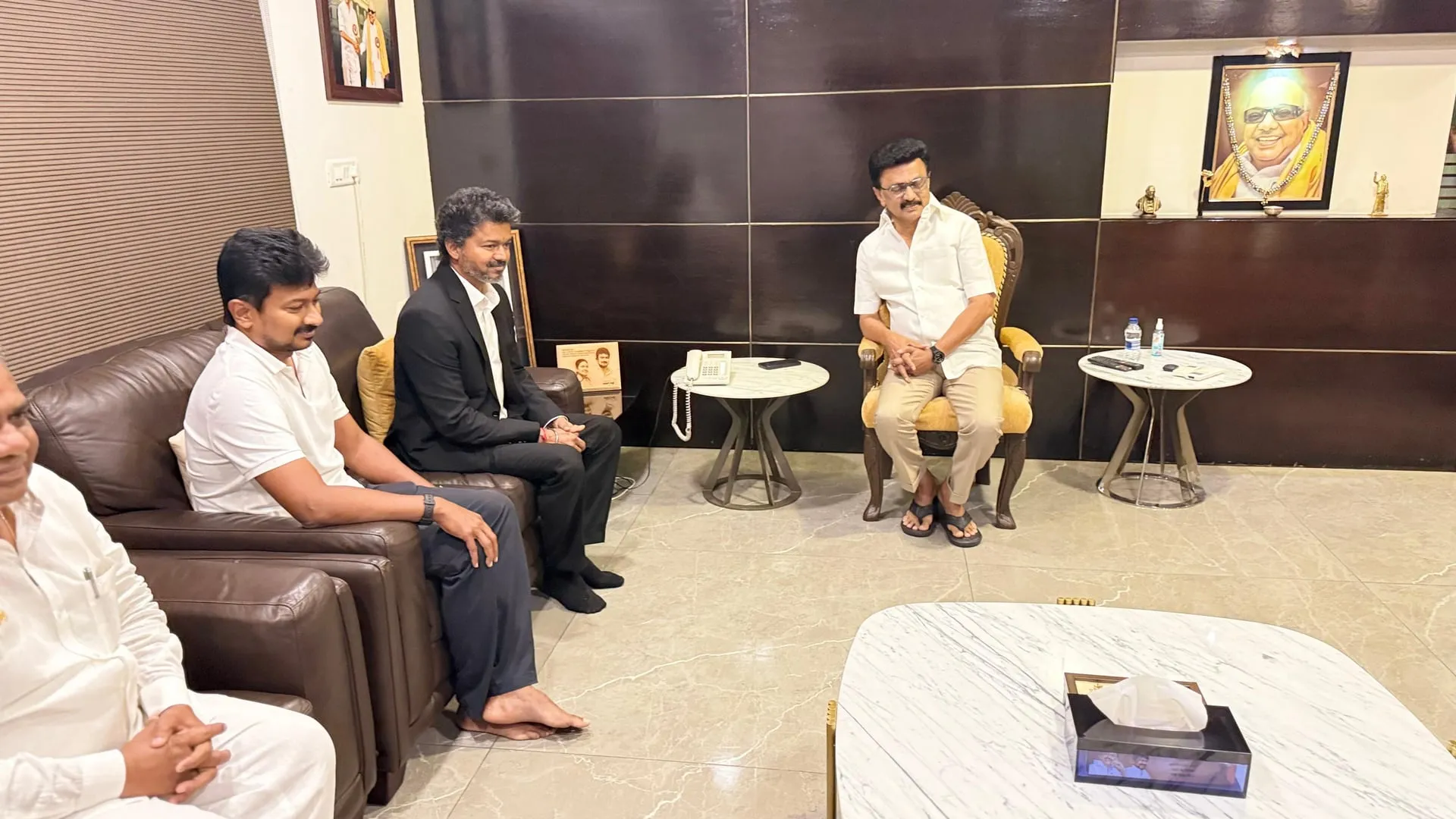 A wider frame from the sit-down, with the three men exchanging notes in the receiving room.
