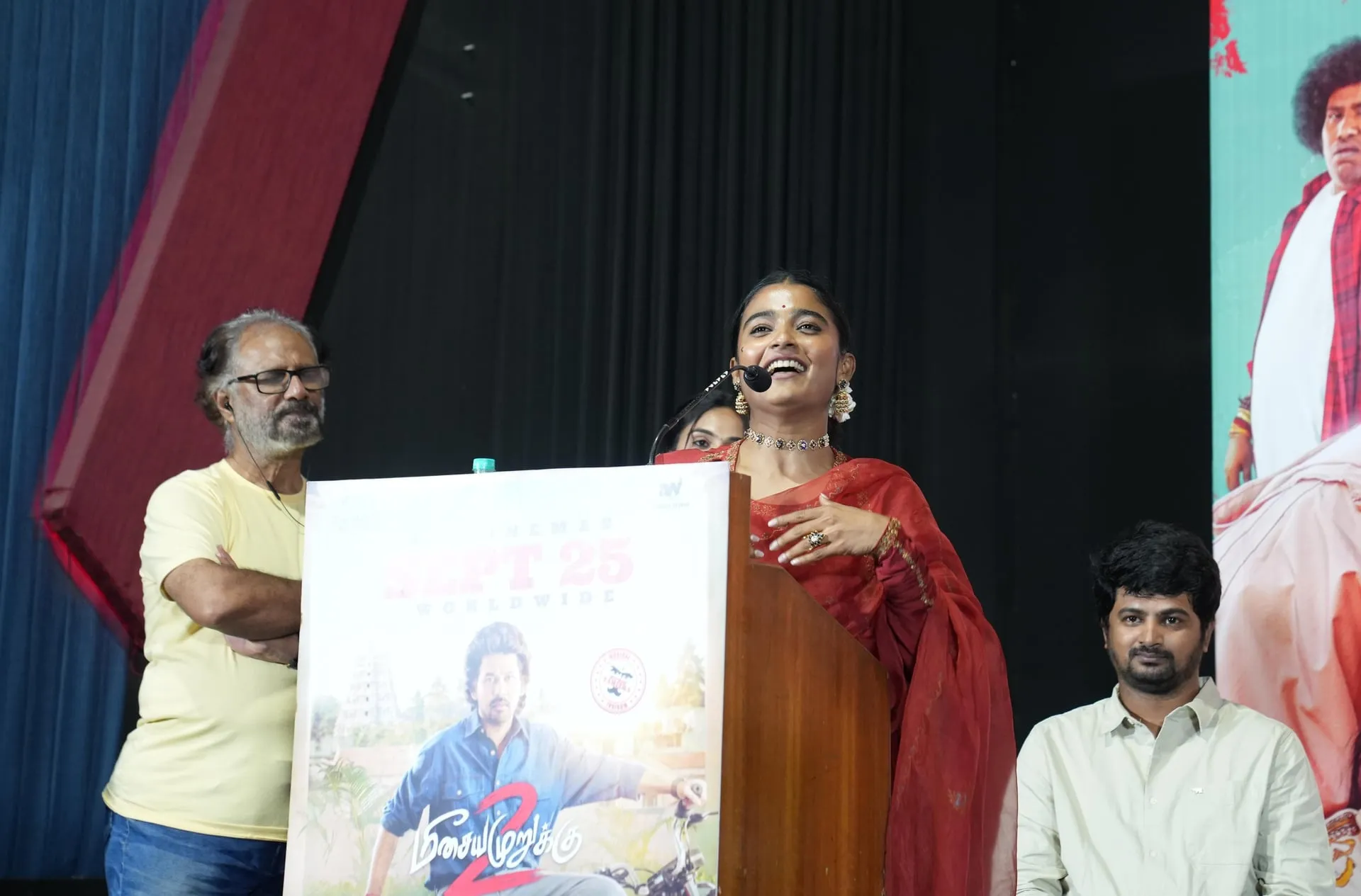 A speaker in red addresses the Meesaya Murukku 2 audience