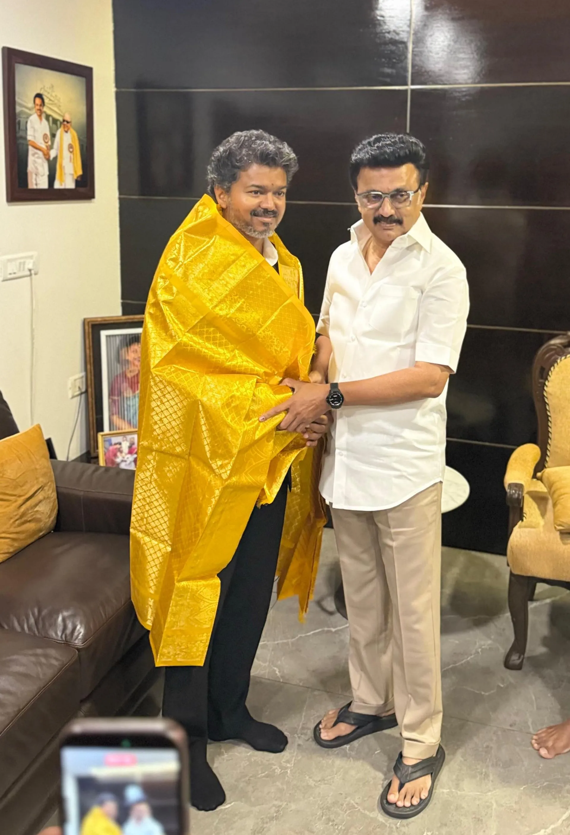 Vijay, draped in the yellow silk shawl Stalin had just gifted him, returns the handshake.