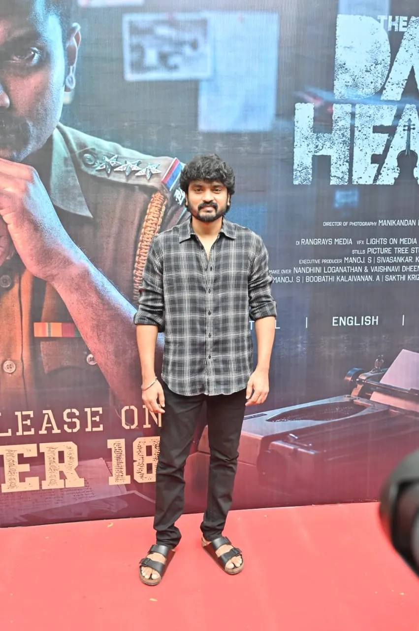 Portrait in a checked shirt in front of The Dark Heaven poster