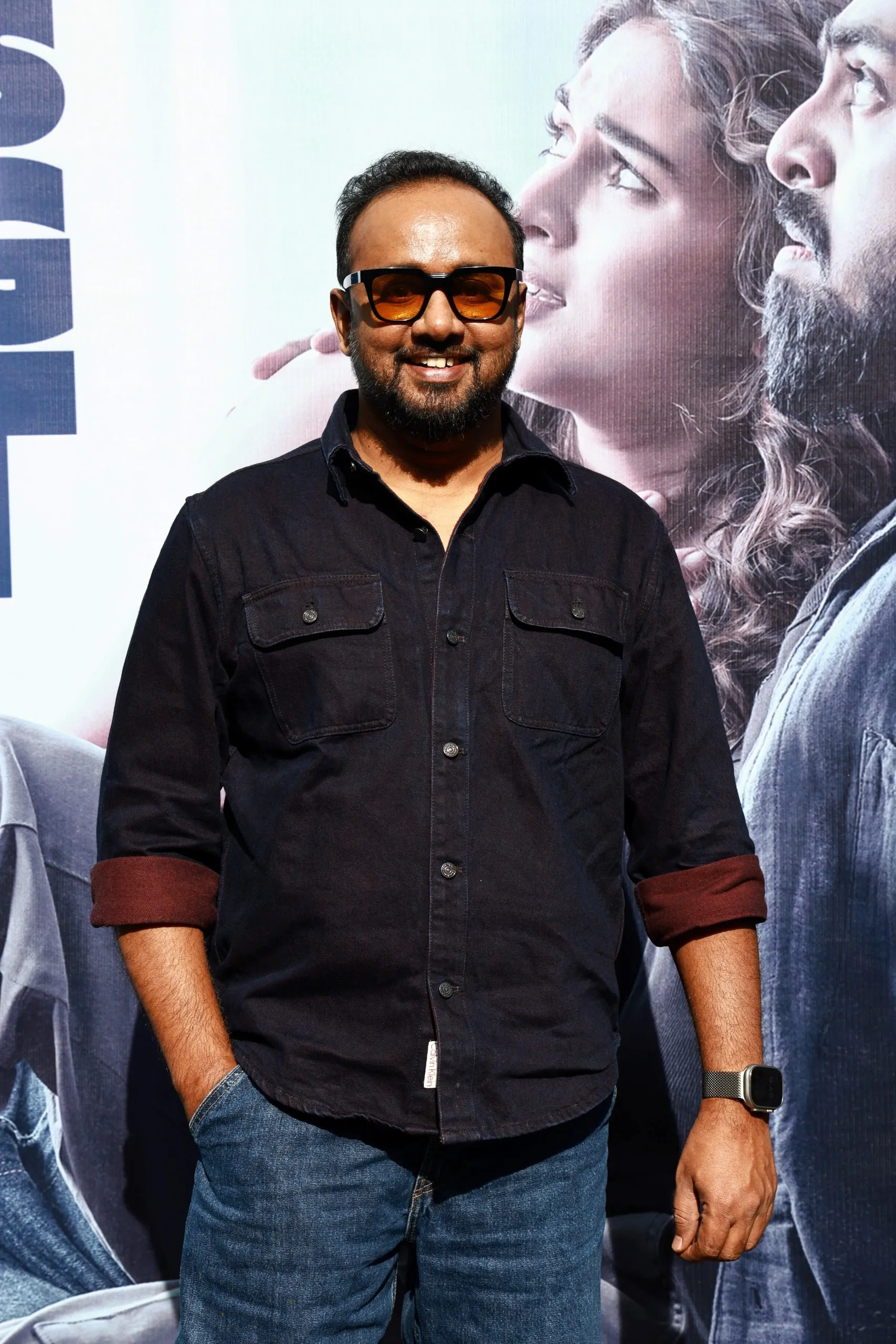 Portrait in a dark shirt and tinted glasses against the Immortal backdrop