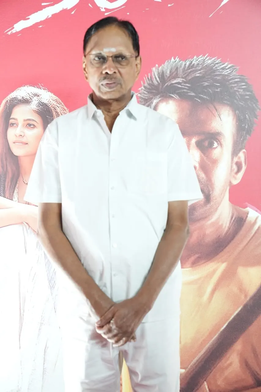 A guest stands before the Yezhu Kadal Yezhu Malai backdrop