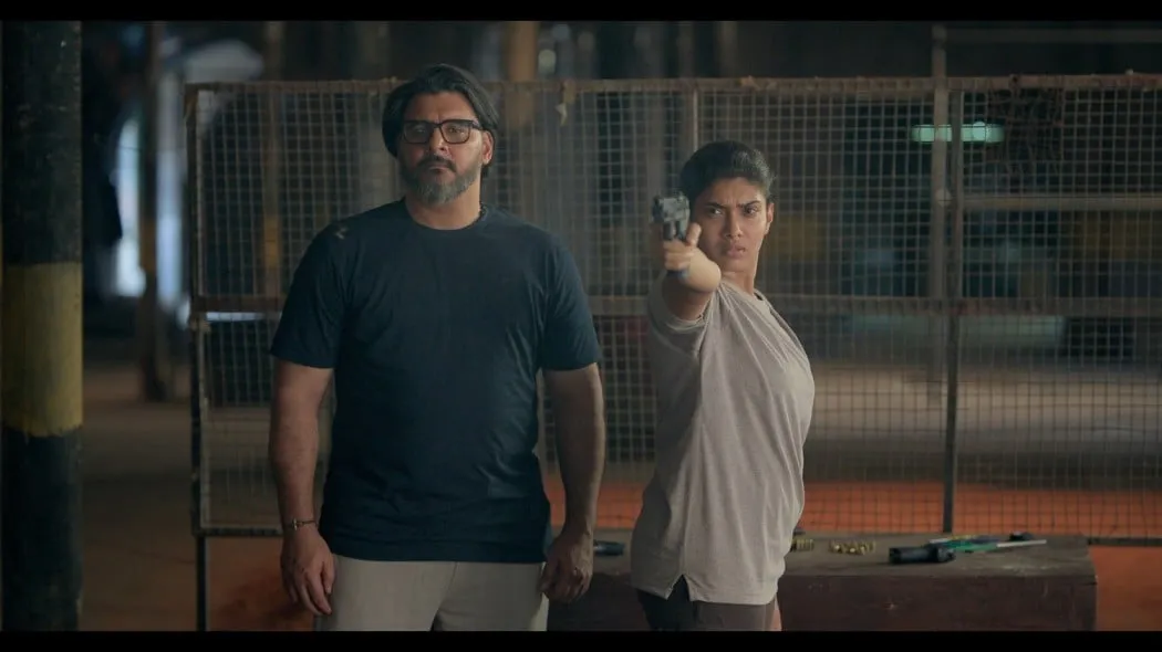 Two characters in a tense night-time confrontation, the woman aiming a service pistol forward.