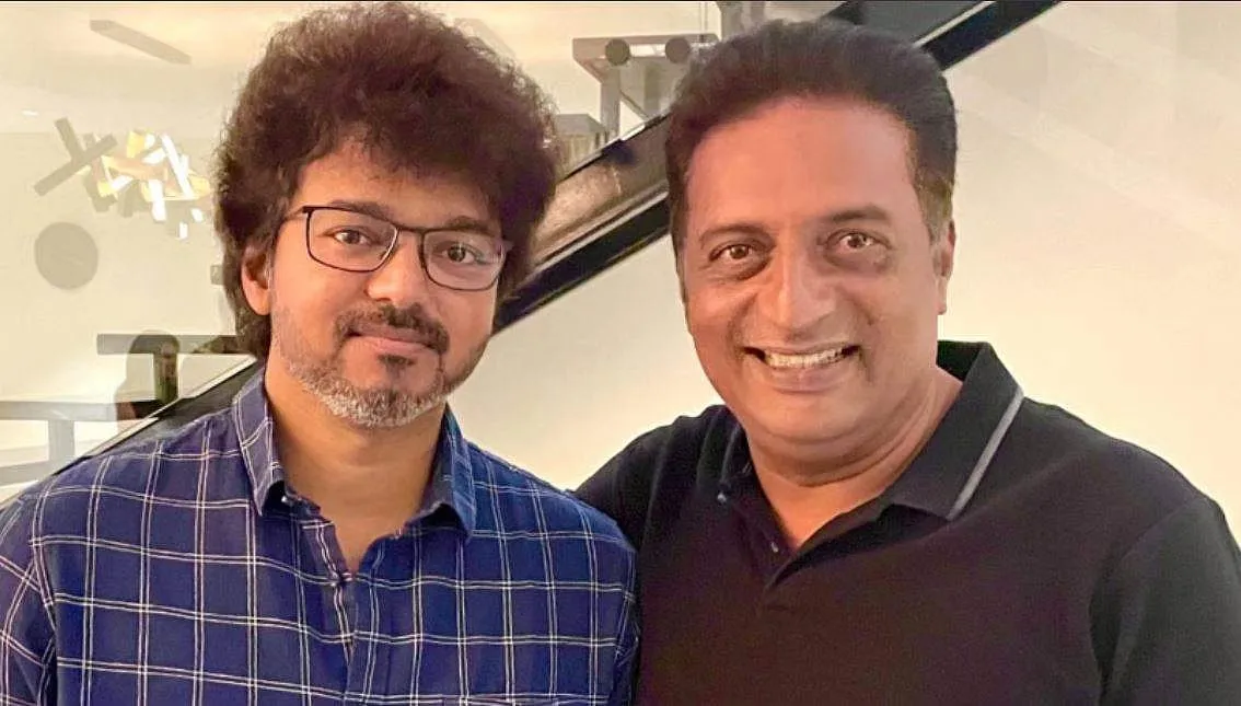 Vijay and Prakash Raj posing together for a portrait, both smiling, in an indoor setting.