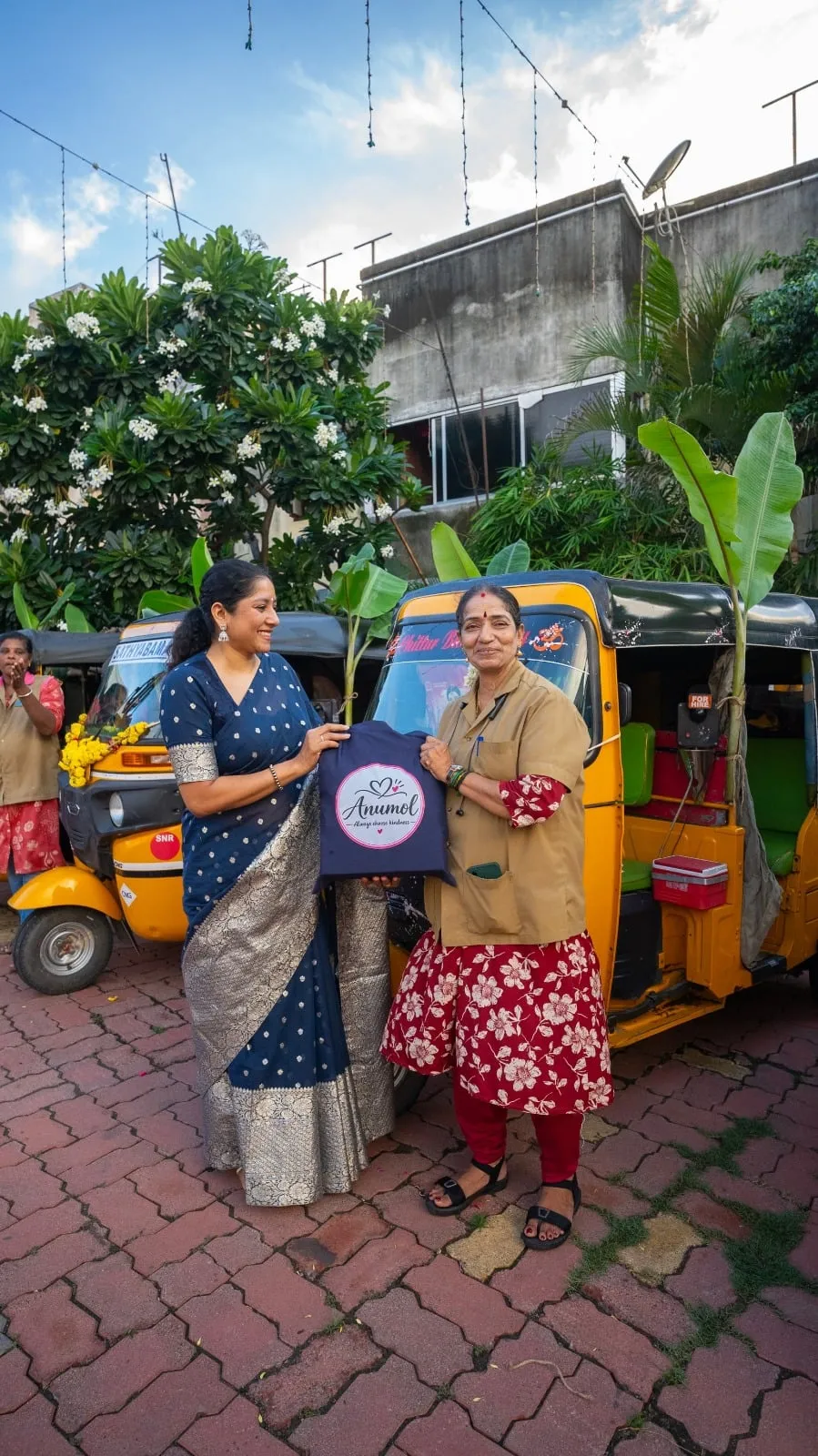 A welfare kit is presented beside an autorickshaw during Anumol's visit.